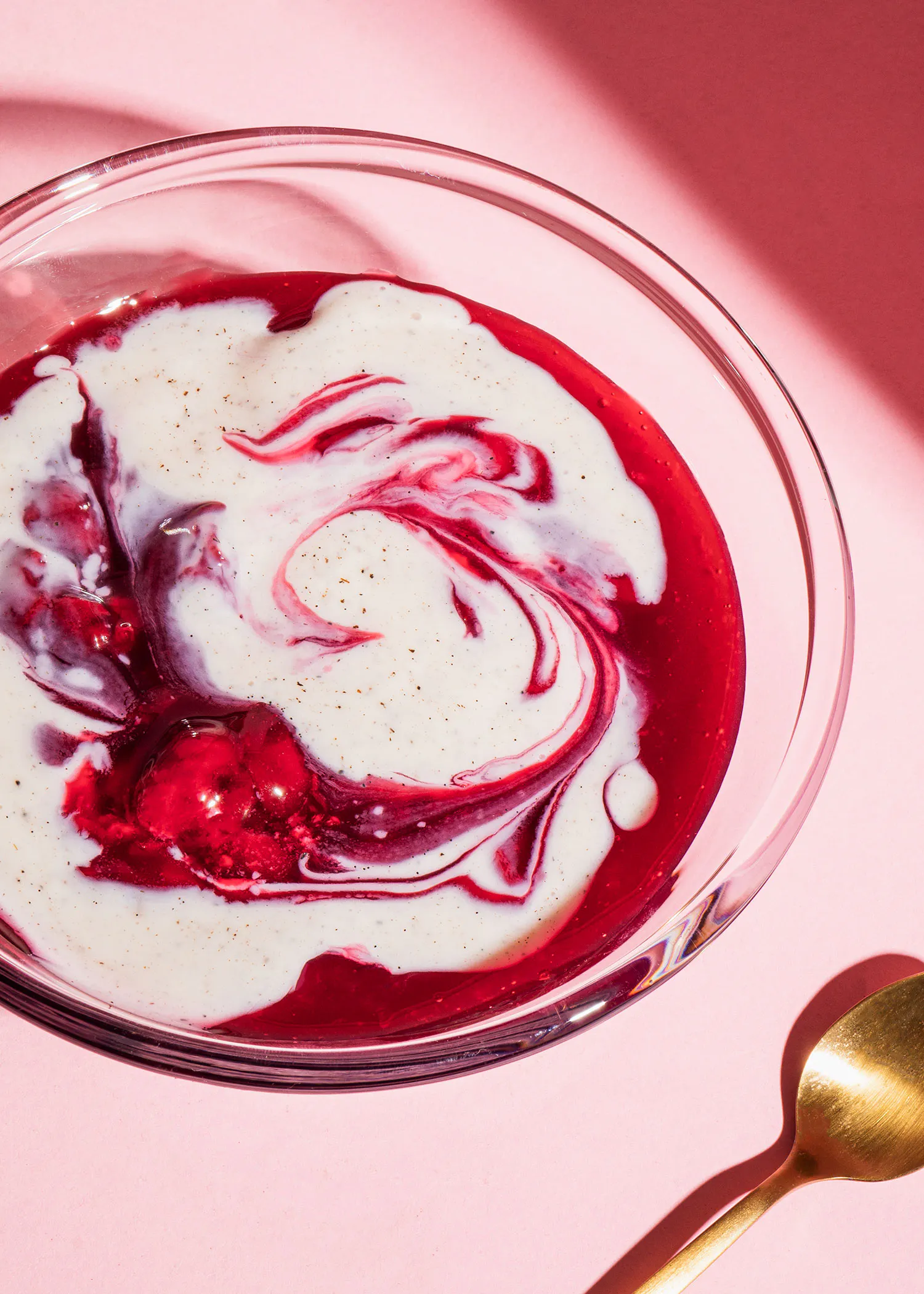 a bowl of yogurt with a swirl of red liquid in it