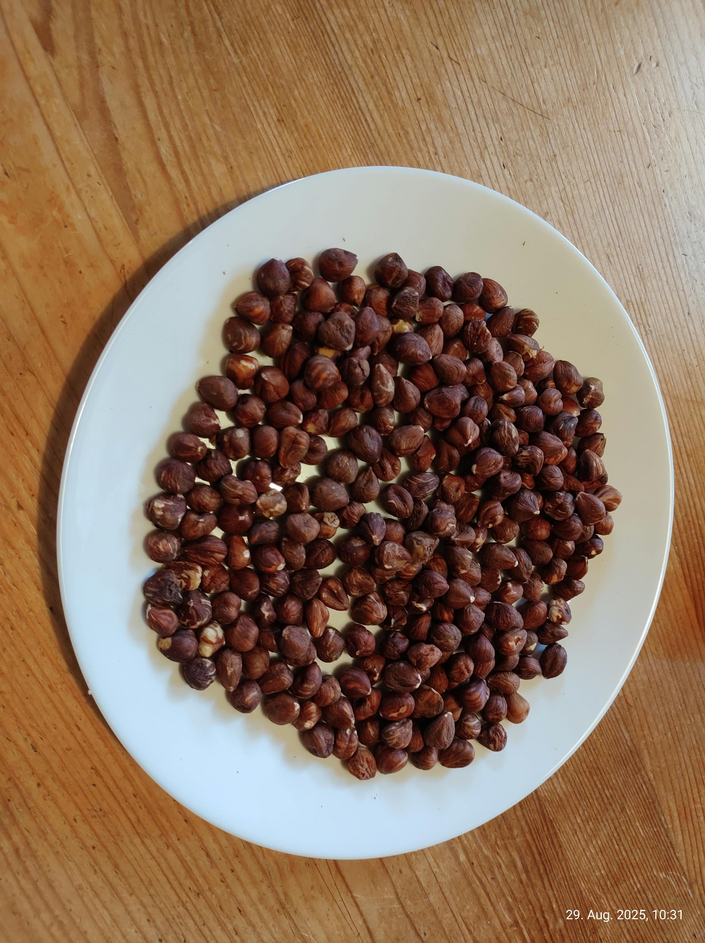 un piatto bianco pieno di noci su un tavolo di legno