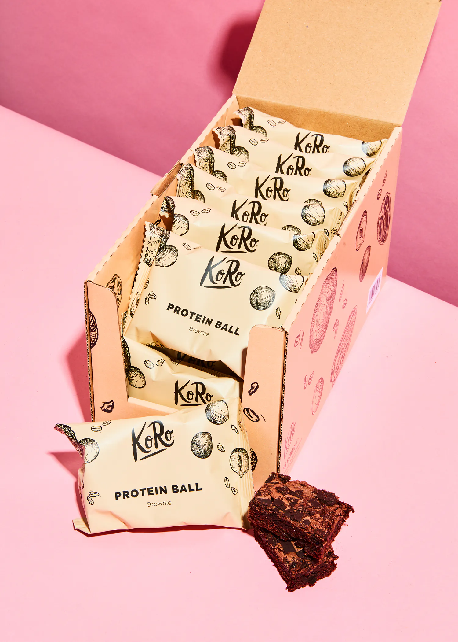 a box of koro protein ball brownies on a pink table
