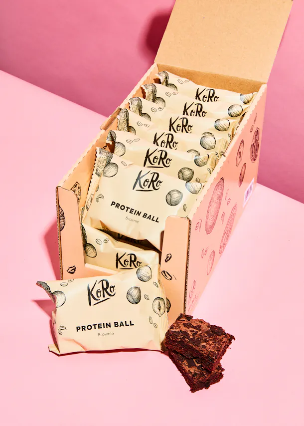 a box of koro protein ball brownies on a pink table