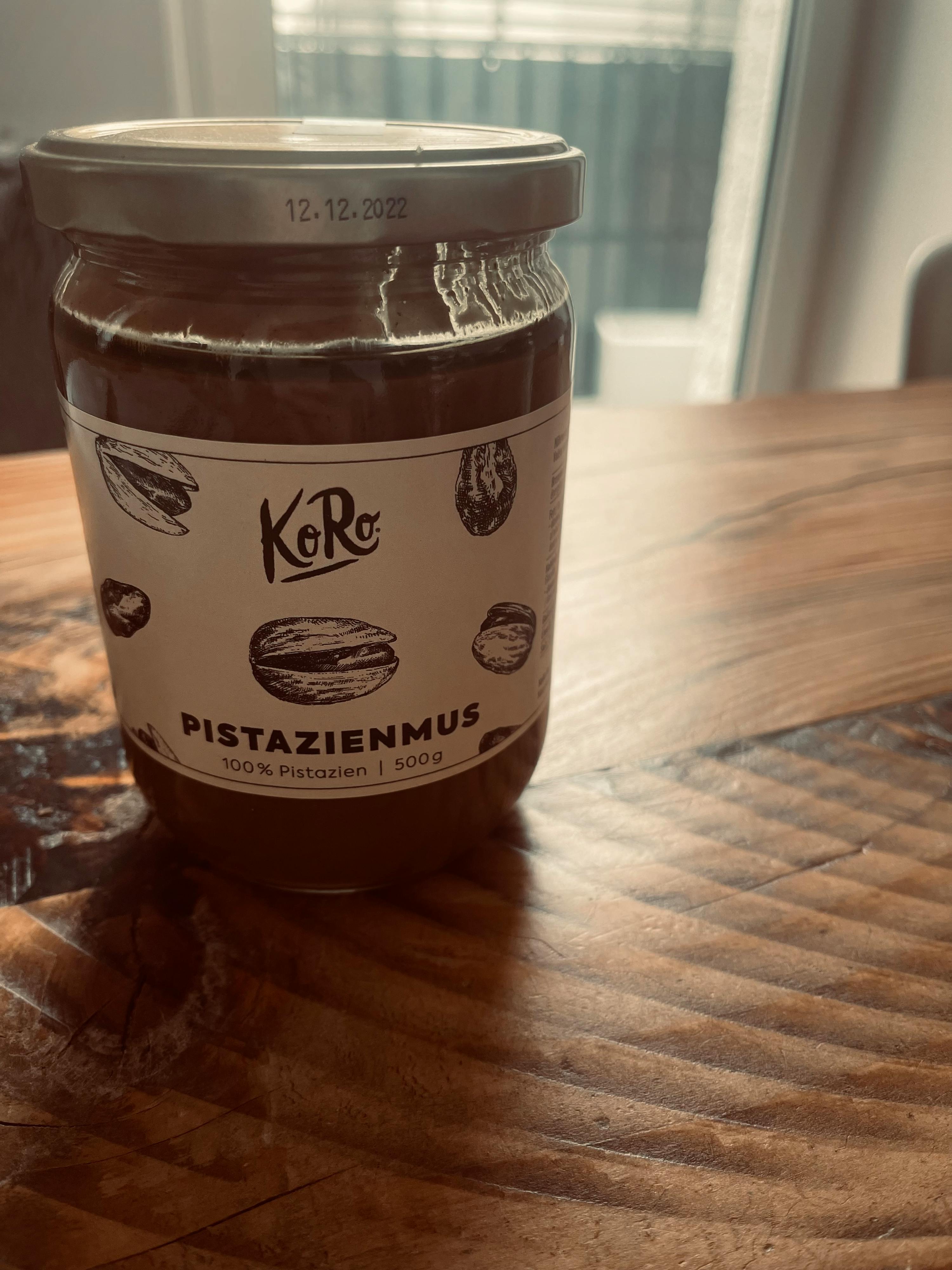 a jar of koro pistazienmus is on a wooden table