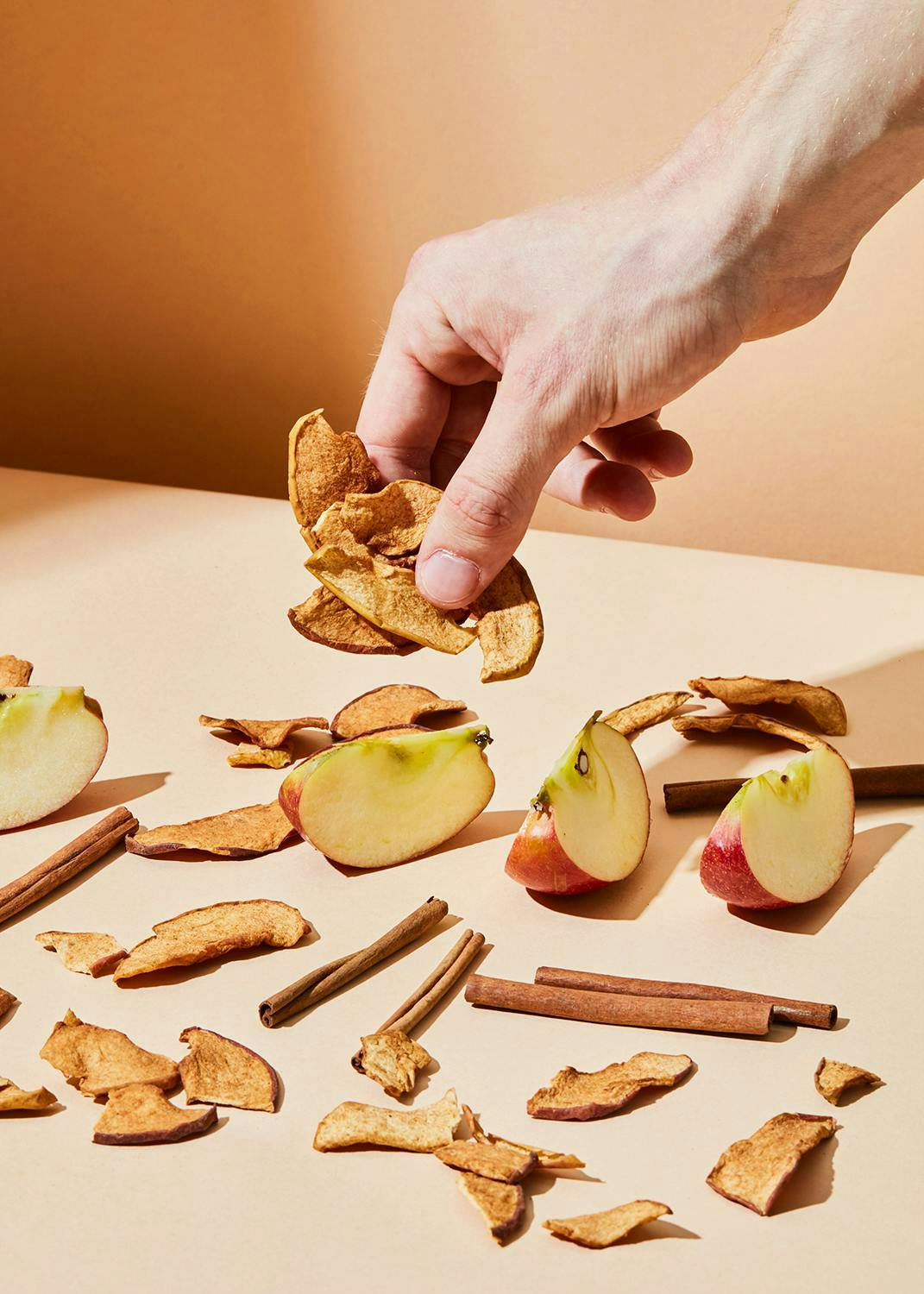 una persona getta una fetta di mela su un tavolo con bastoncini di cannella