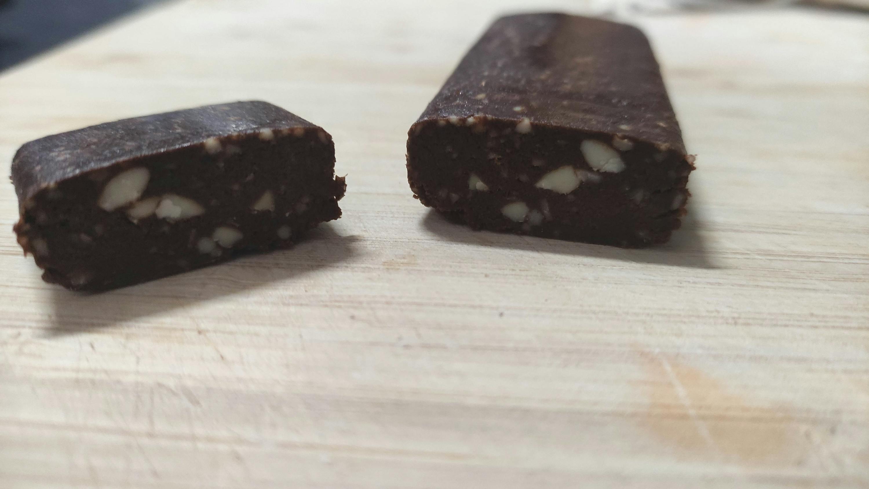 two pieces of chocolate are sitting on a wooden cutting board