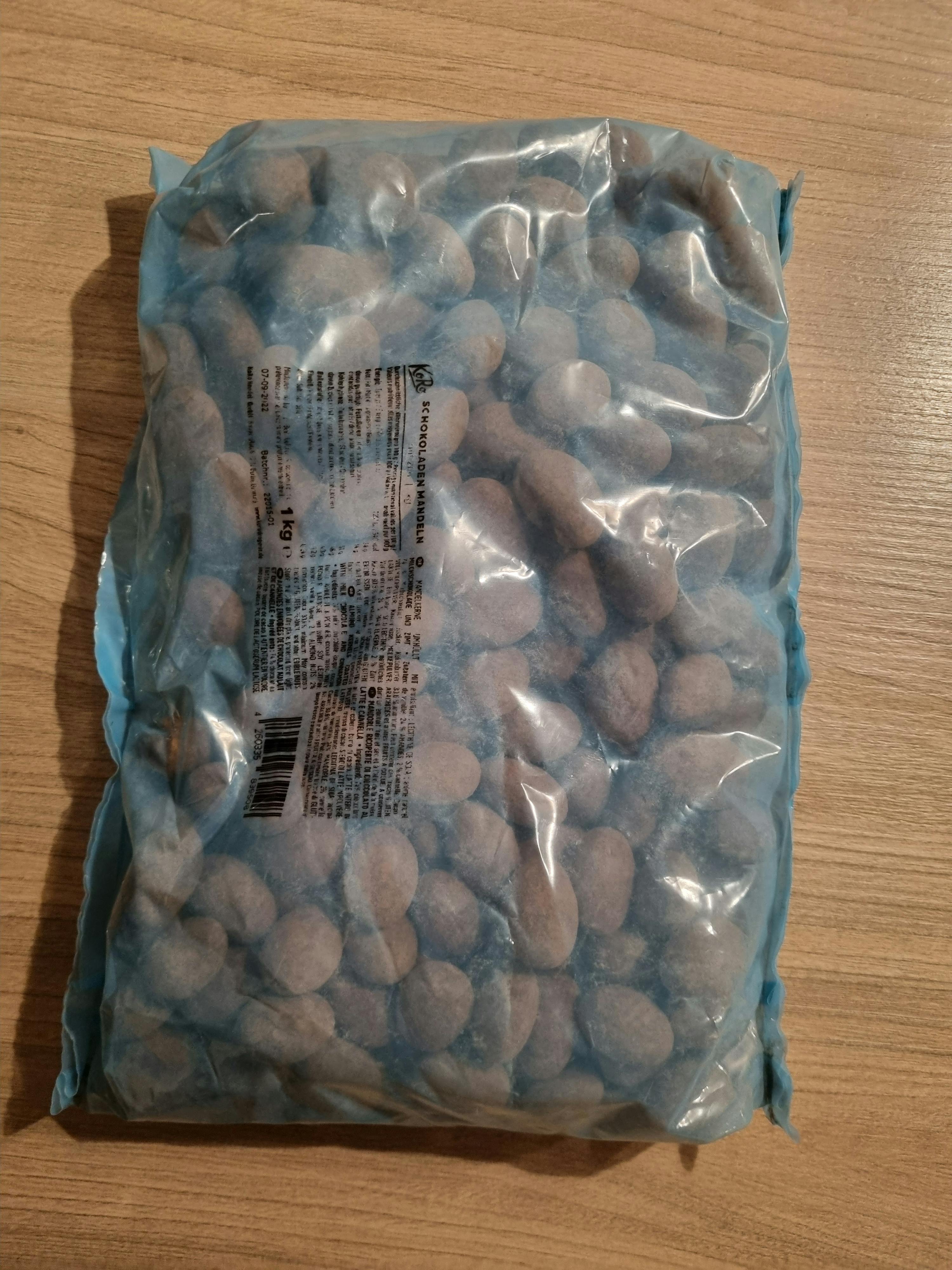 eine Tüte Schokoladen-Mandeln liegt auf einem Holztisch
