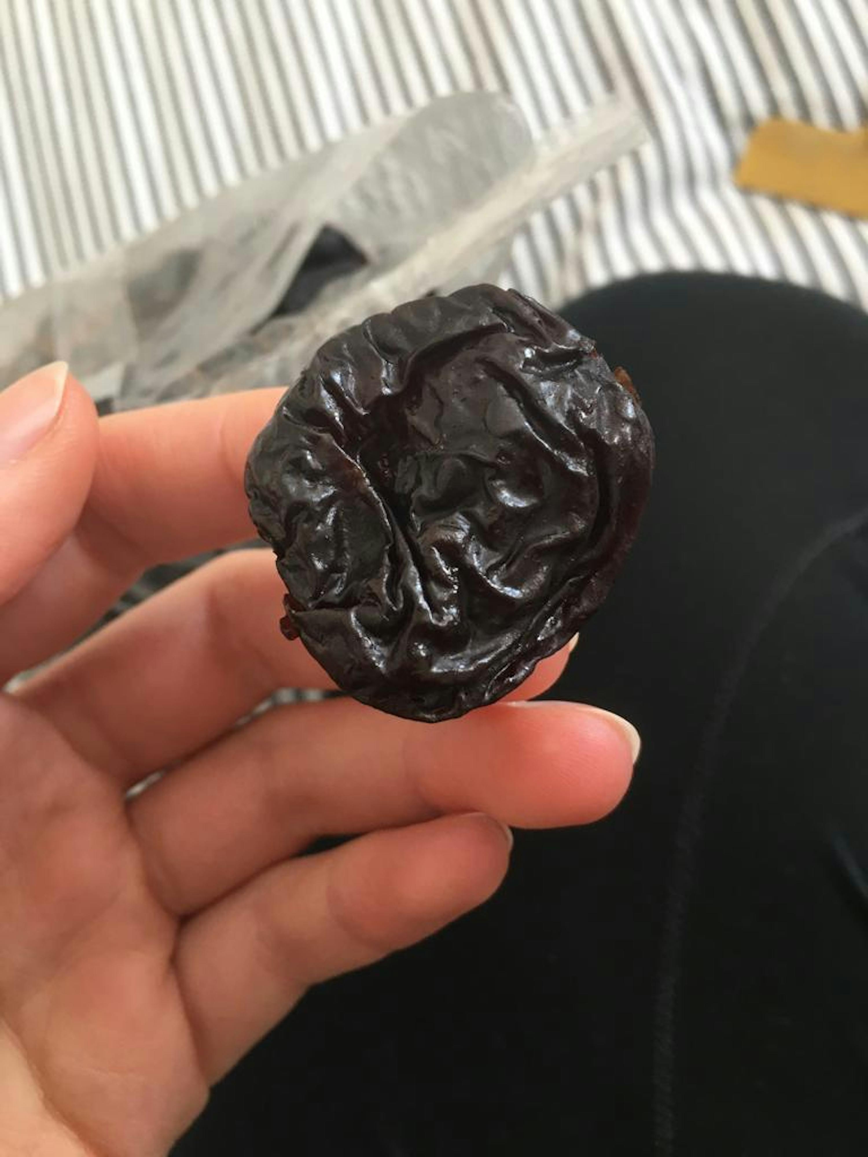 une personne tient une prune noire dans sa main