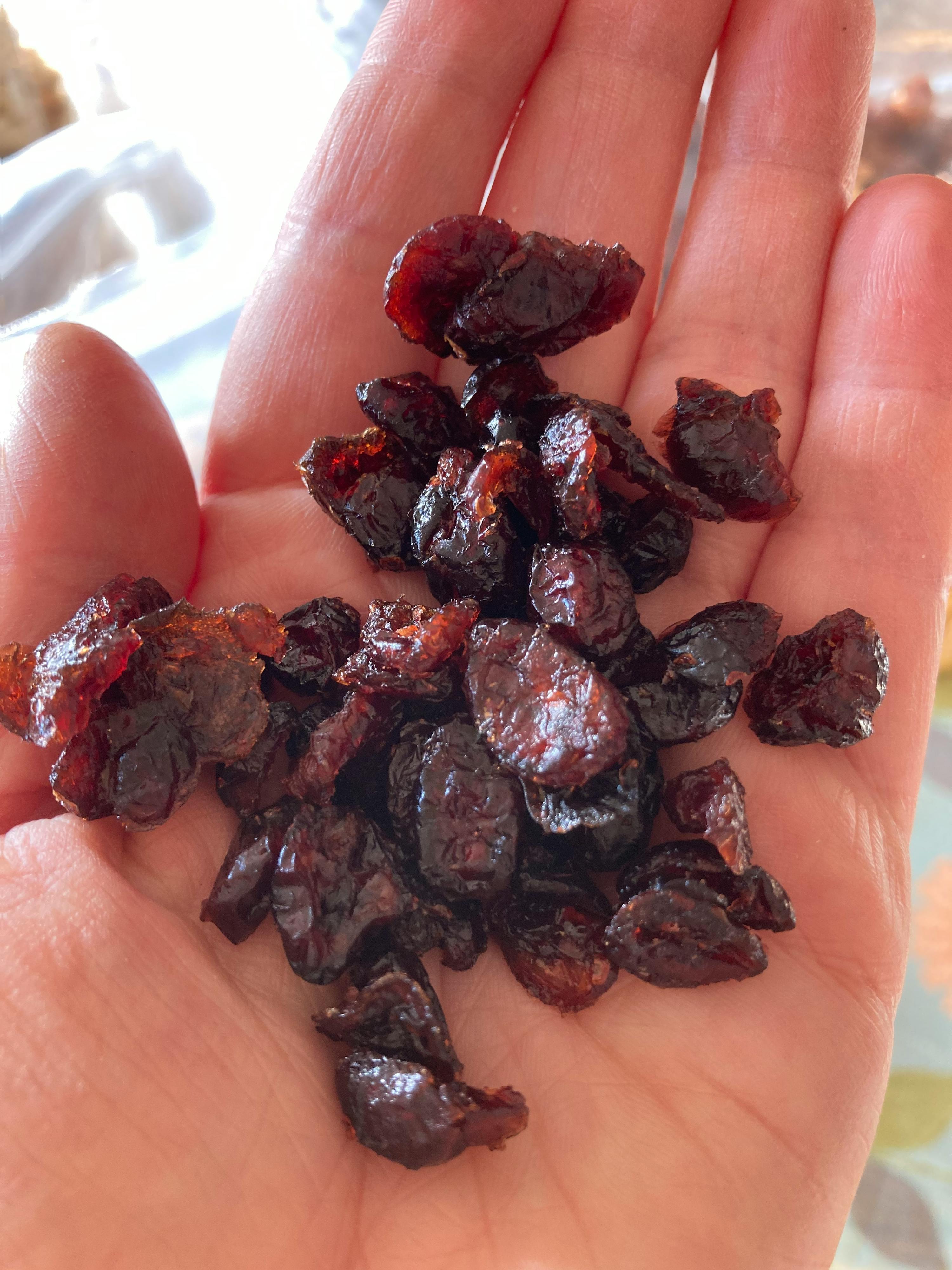 eine Person hält einen Haufen getrockneter Kirschen in der Hand