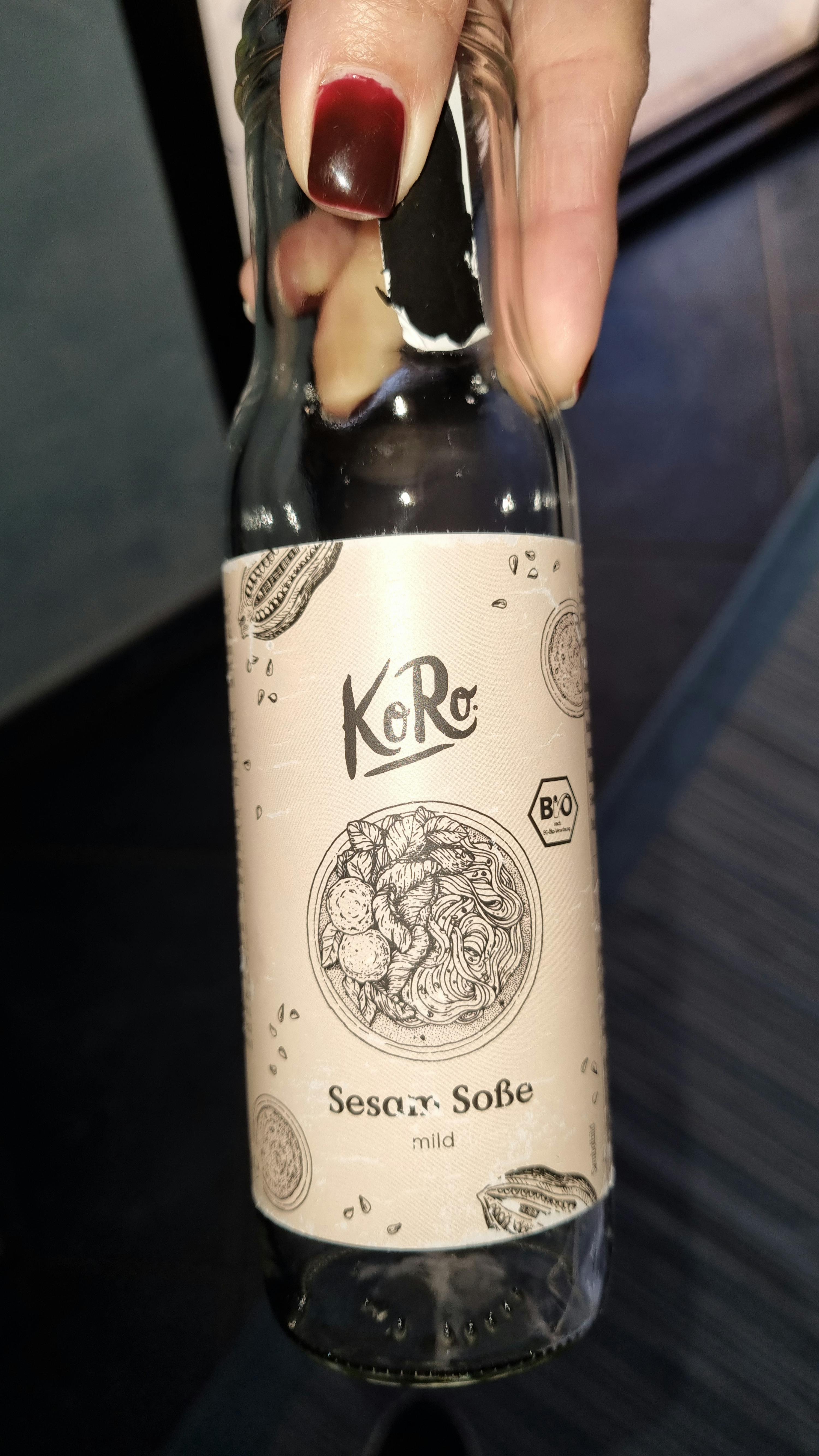 Eine Person hält eine Flasche Sesam-Soße in der Hand