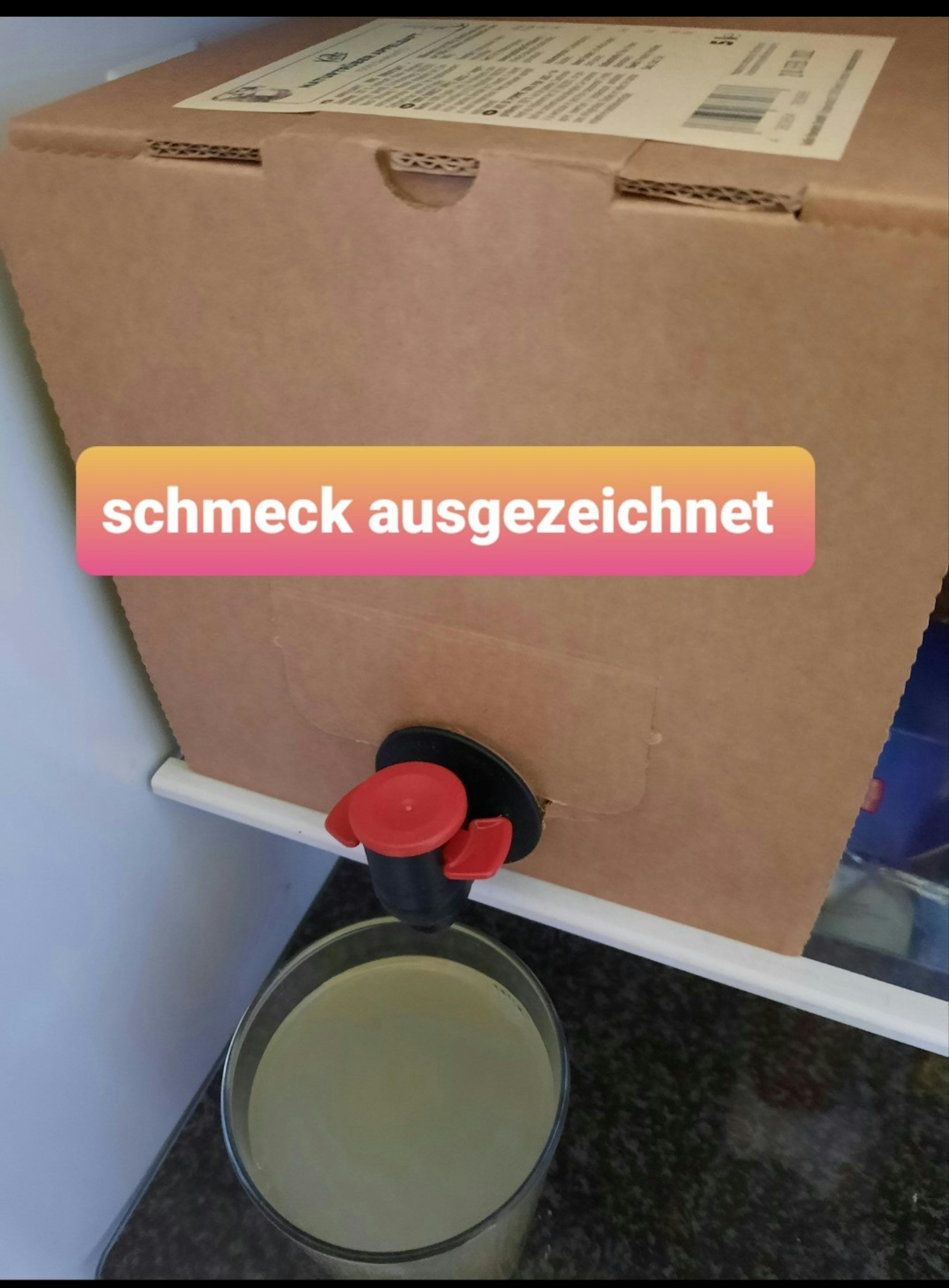 une boîte en carton avec un robinet rouge à côté d' un verre d' eau