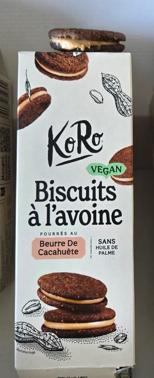 eine verpackung von koro veganen haferkeksen mit erdnussbutterfüllung, auf der ein einzelner keks oben auf der packung liegt.
