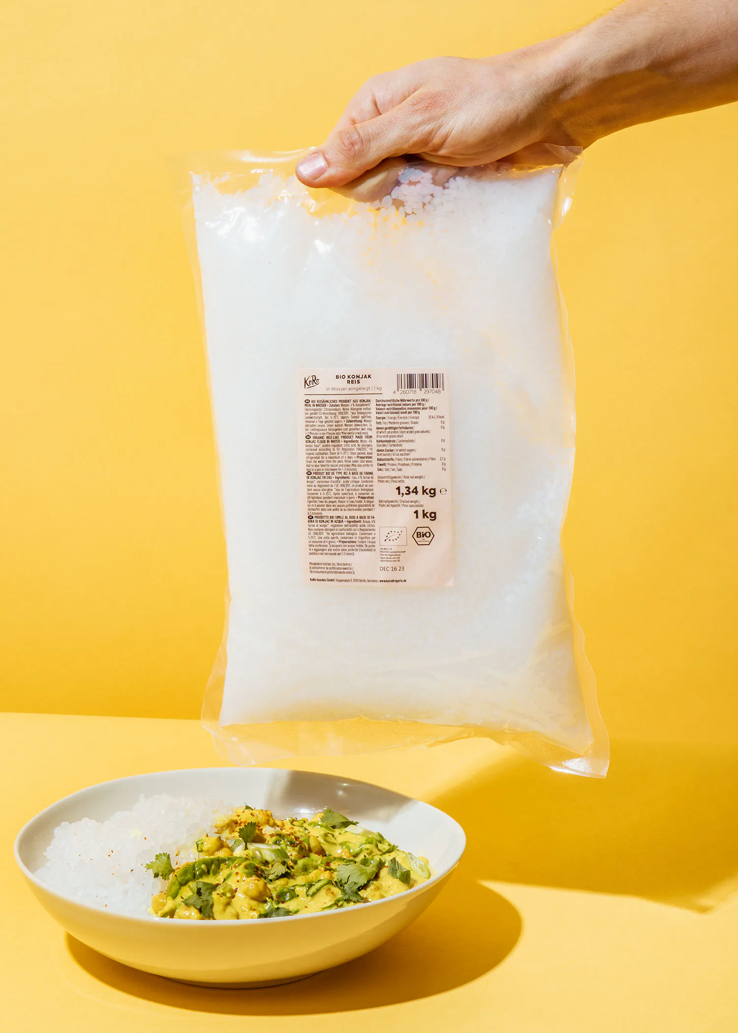 eine Person hält einen Plastikbeutel mit einem Gewicht von 1,34 kg neben einem Teller Reis