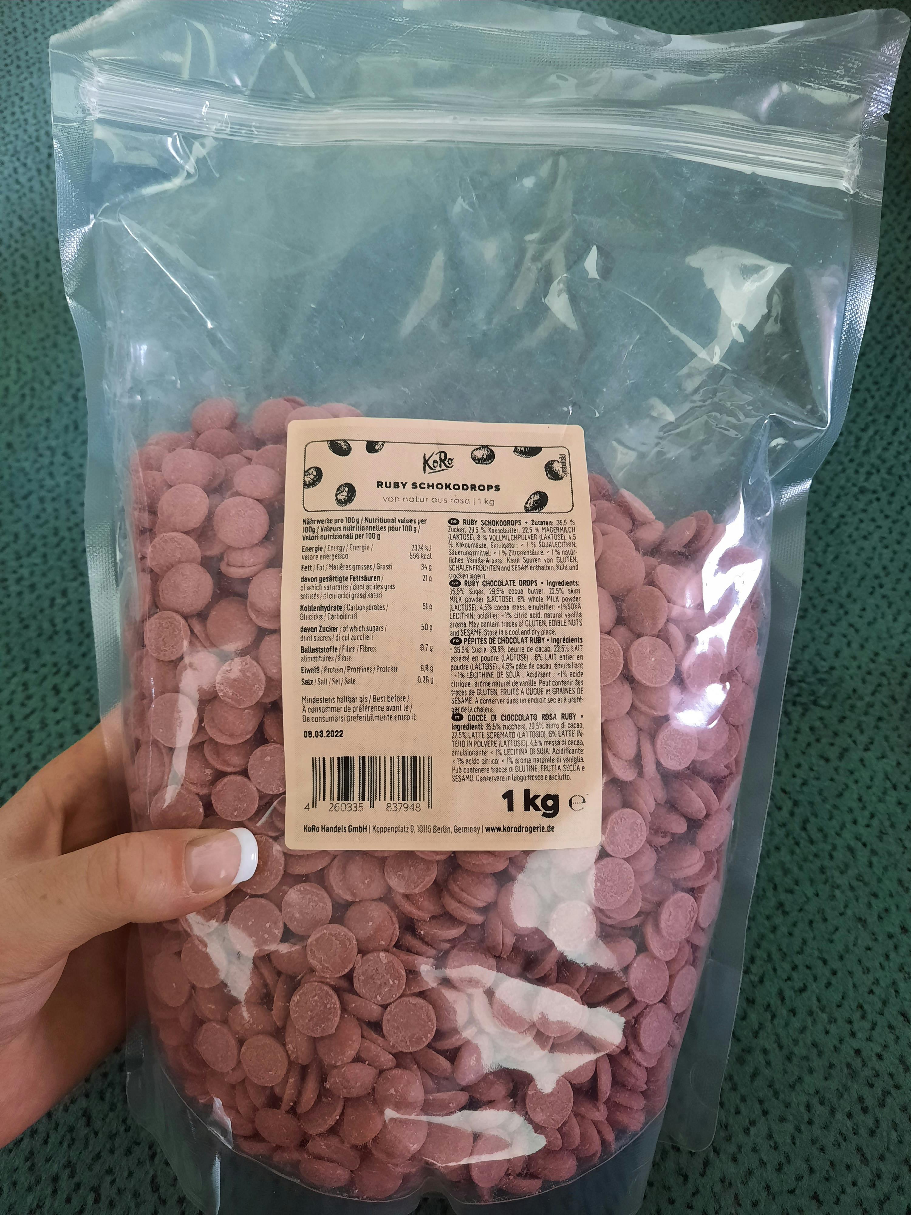 eine Person hält einen Plastikbeutel mit rosa Schokoladenchips in der Hand