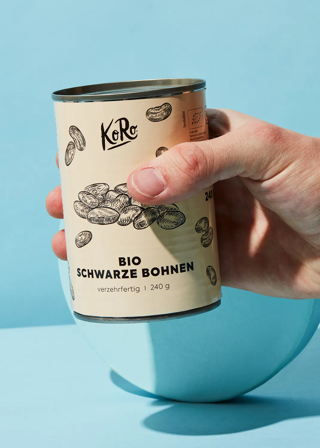 une personne tient une boîte de haricots noirs bio