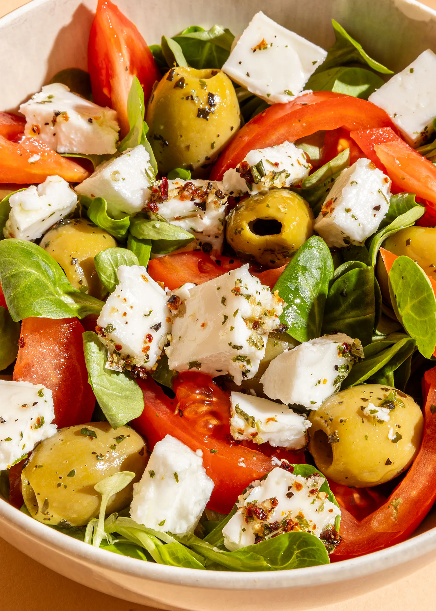 un gros plan d' une salade avec des tomates des olives et du fromage