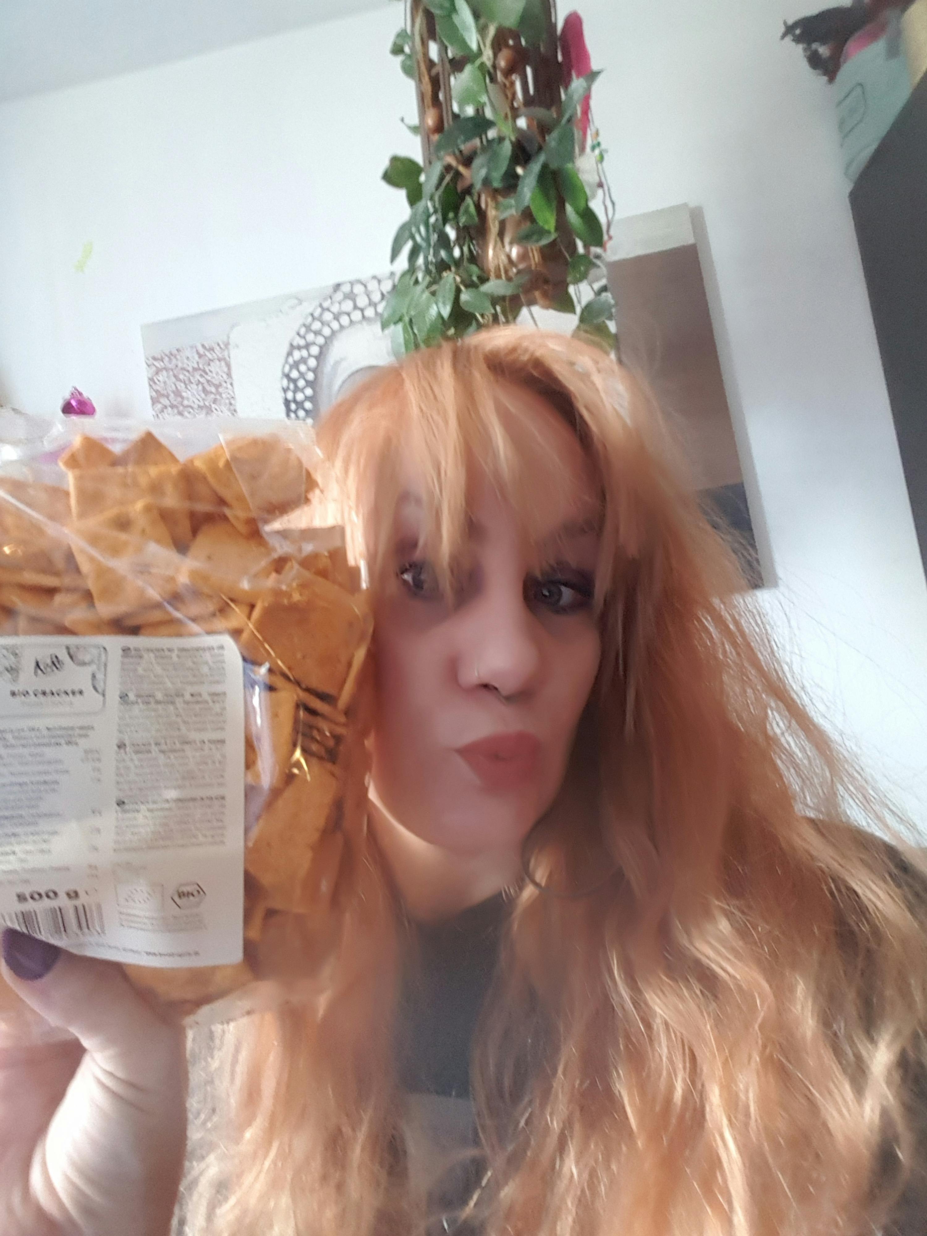 una donna con i capelli rossi tiene in mano un sacchetto di crackers