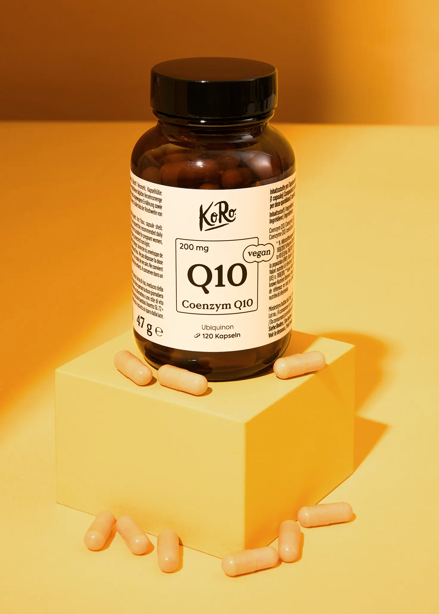 a bottle of coenzym q10 capsules sitting on a yellow cube