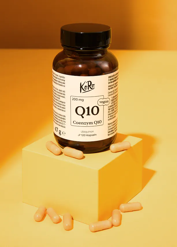 a bottle of coenzym q10 capsules sitting on a yellow cube