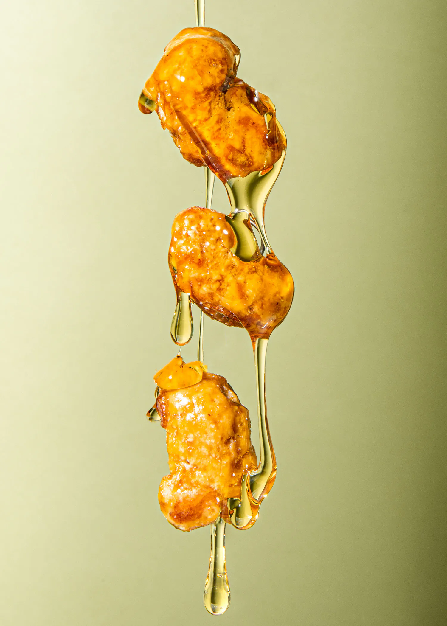 three pieces of chicken are being drizzled with honey