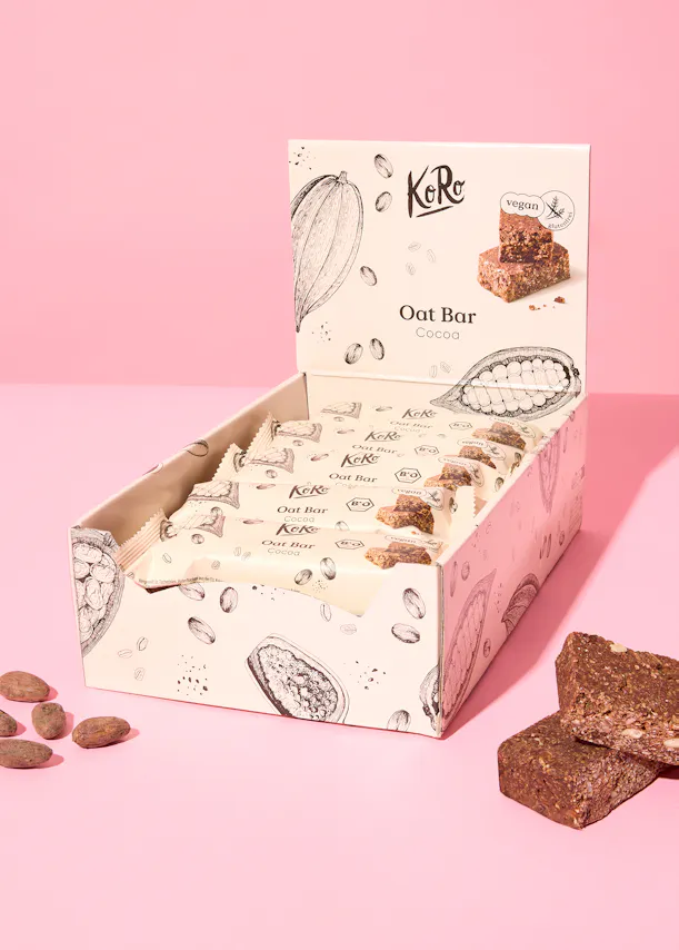 eine Schachtel Oat-Bars steht auf einem rosa Hintergrund