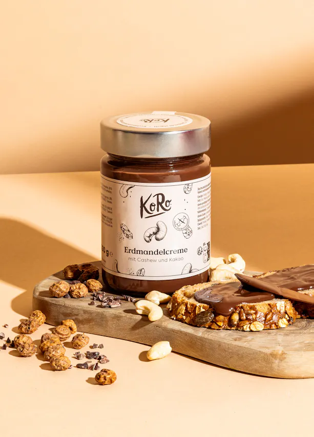 un bocal de crème de cacahuètes et de noix assis sur une planche à découper en bois