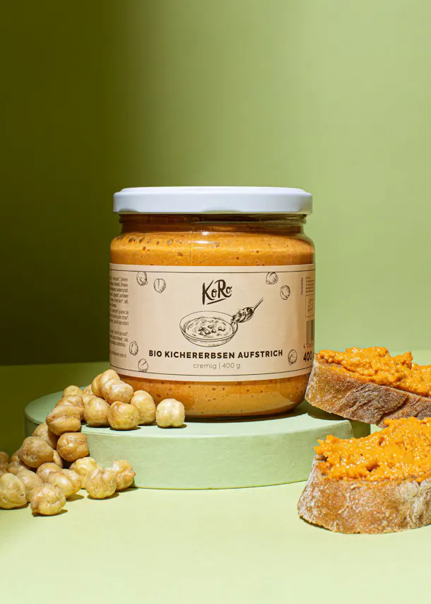 ein Glas bio Kichererbsen aufstrich steht neben einem Stück Brot