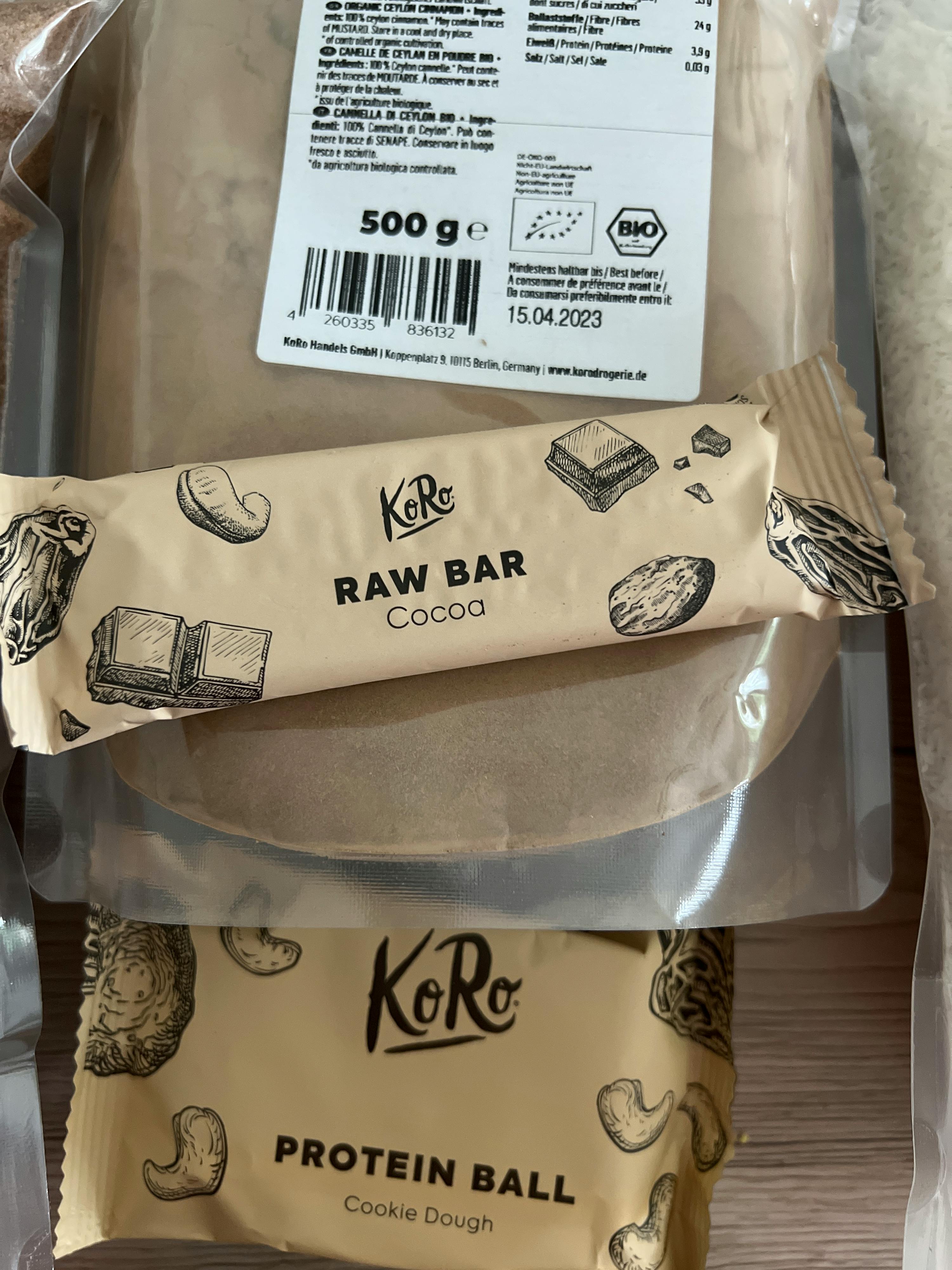 a package of raw bar cocoa sits next to a package of protein ball cookie dough