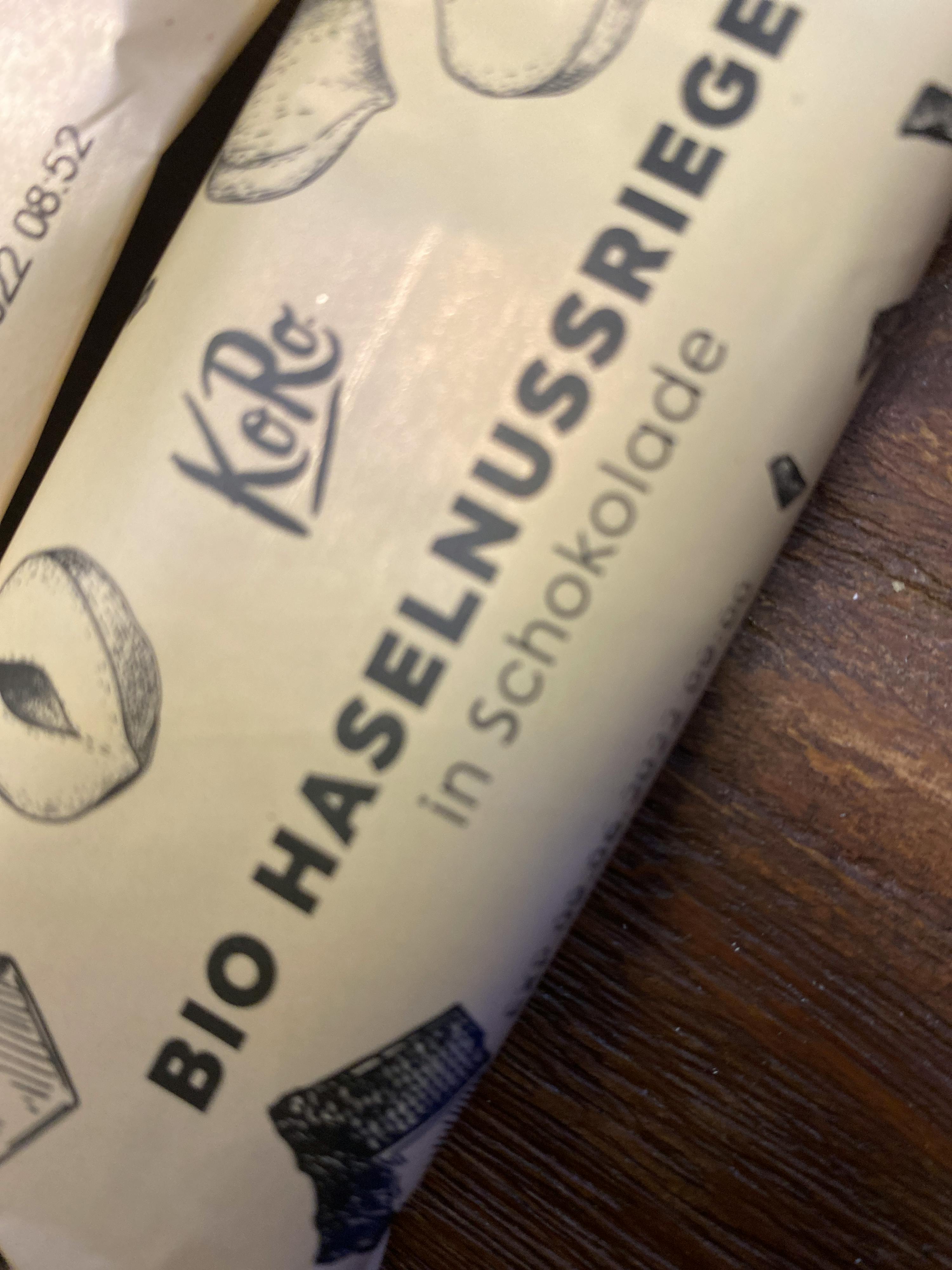 ein Stück Bio-Haselnussriege-Schokolade liegt auf einem Holztisch
