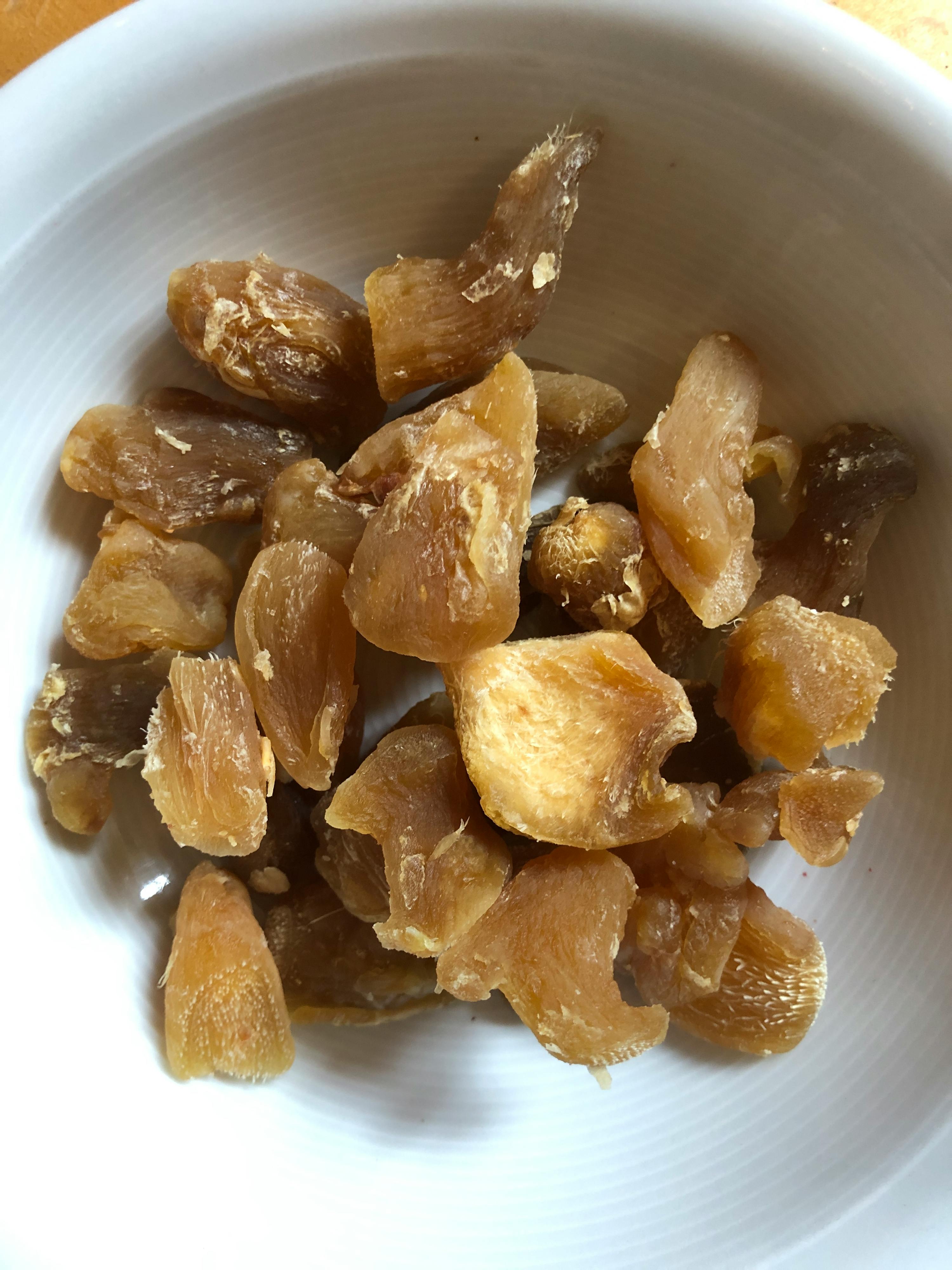 a white bowl filled with pieces of dried ginger