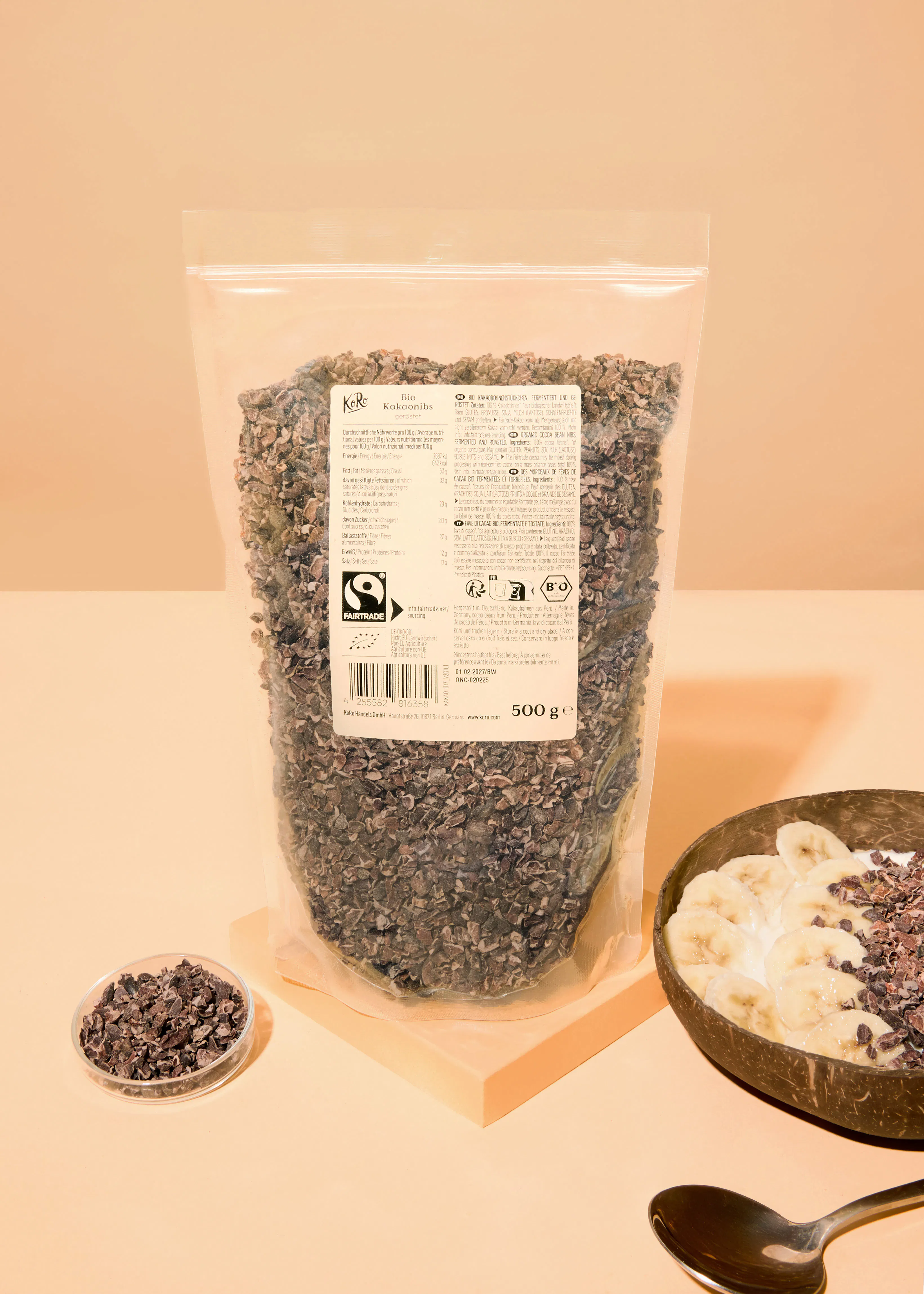 un grand sac de 500g de fèves de cacao bio kero est posé à côté d'un bol de yaourt avec des bananes et des fèves de cacao, et d'une petite coupelle de fèves de cacao.