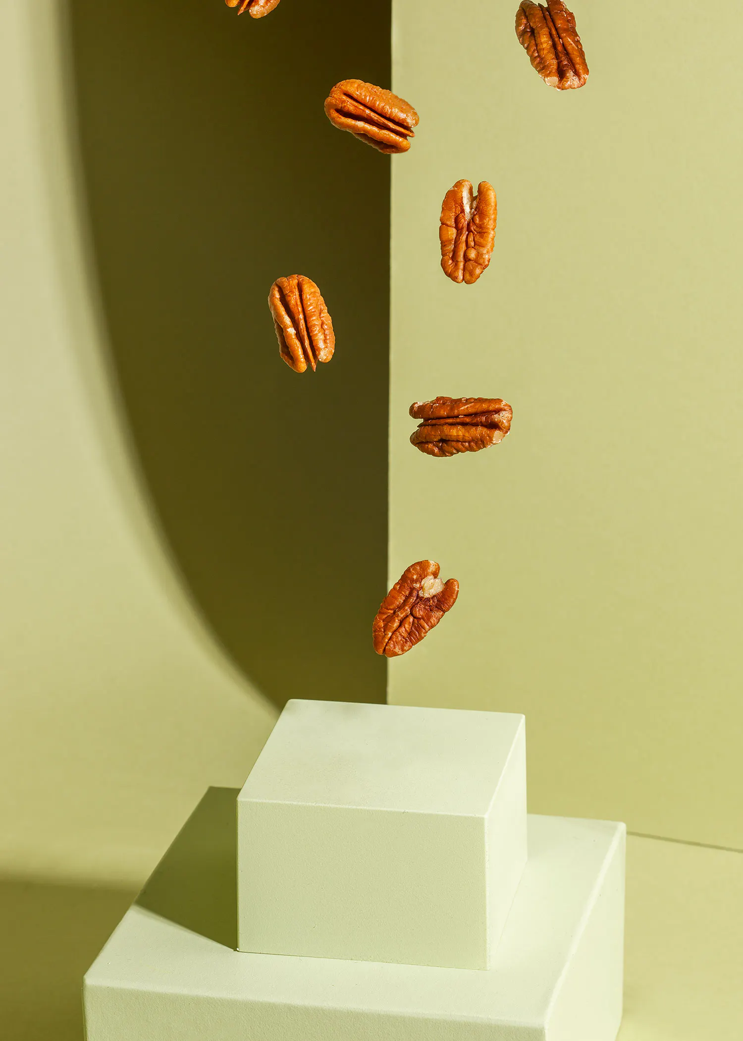 pecans falling into a white box on a green background