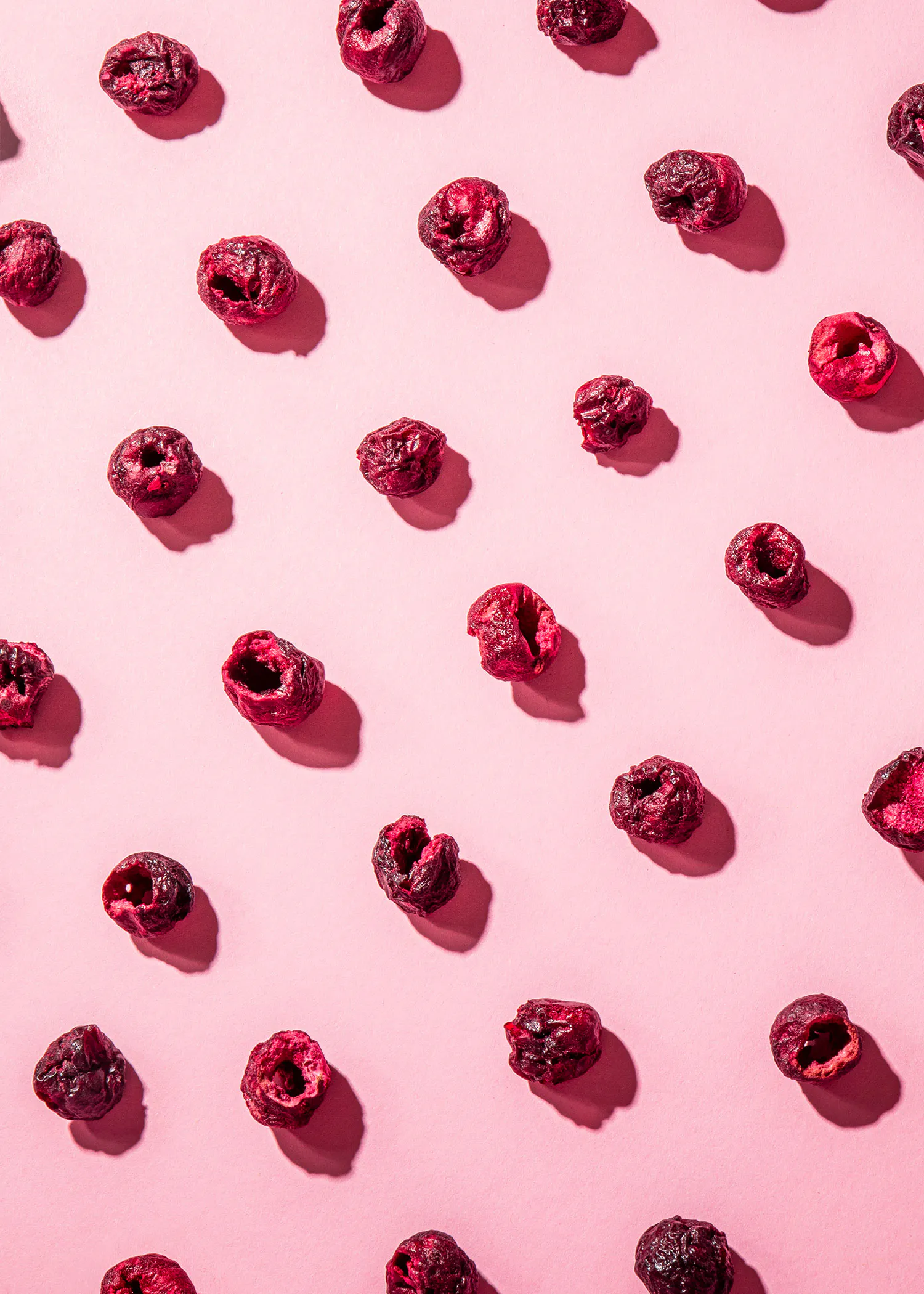 a pattern of dried raspberries on a pink surface
