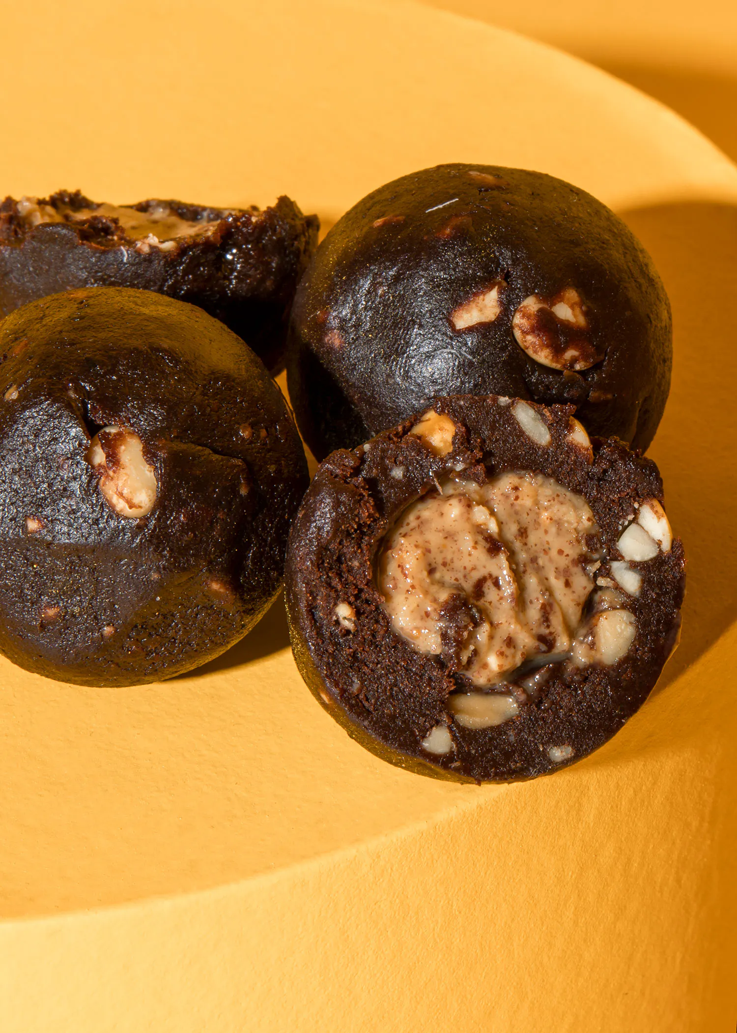 trois brownies sont posés sur une surface jaune et l' un d' entre eux a été coupé en deux