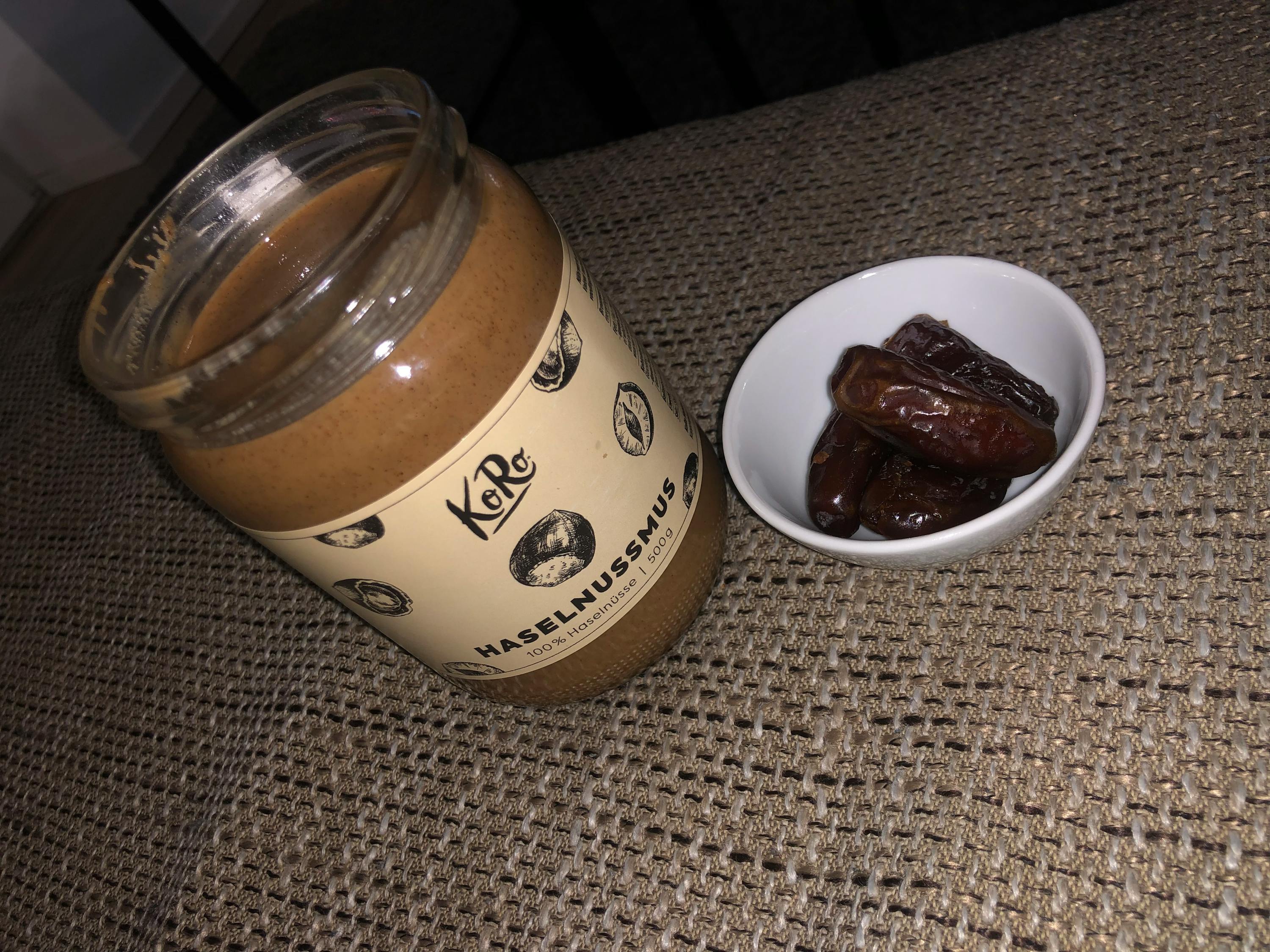 a jar of hazelnusmus next to a small bowl of dates