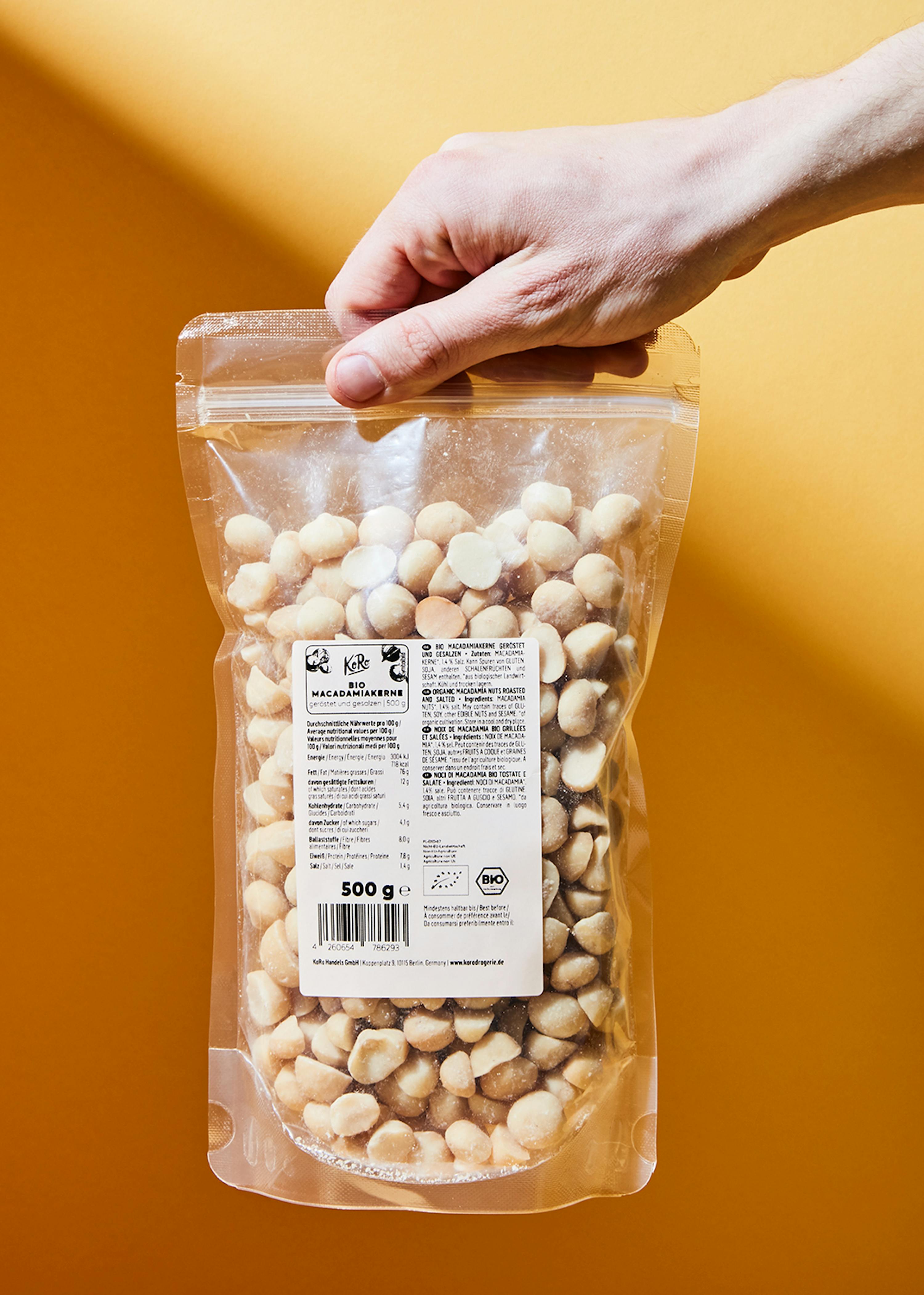 eine Person hält einen Plastikbeutel mit macadamia-Nüssen in der Hand