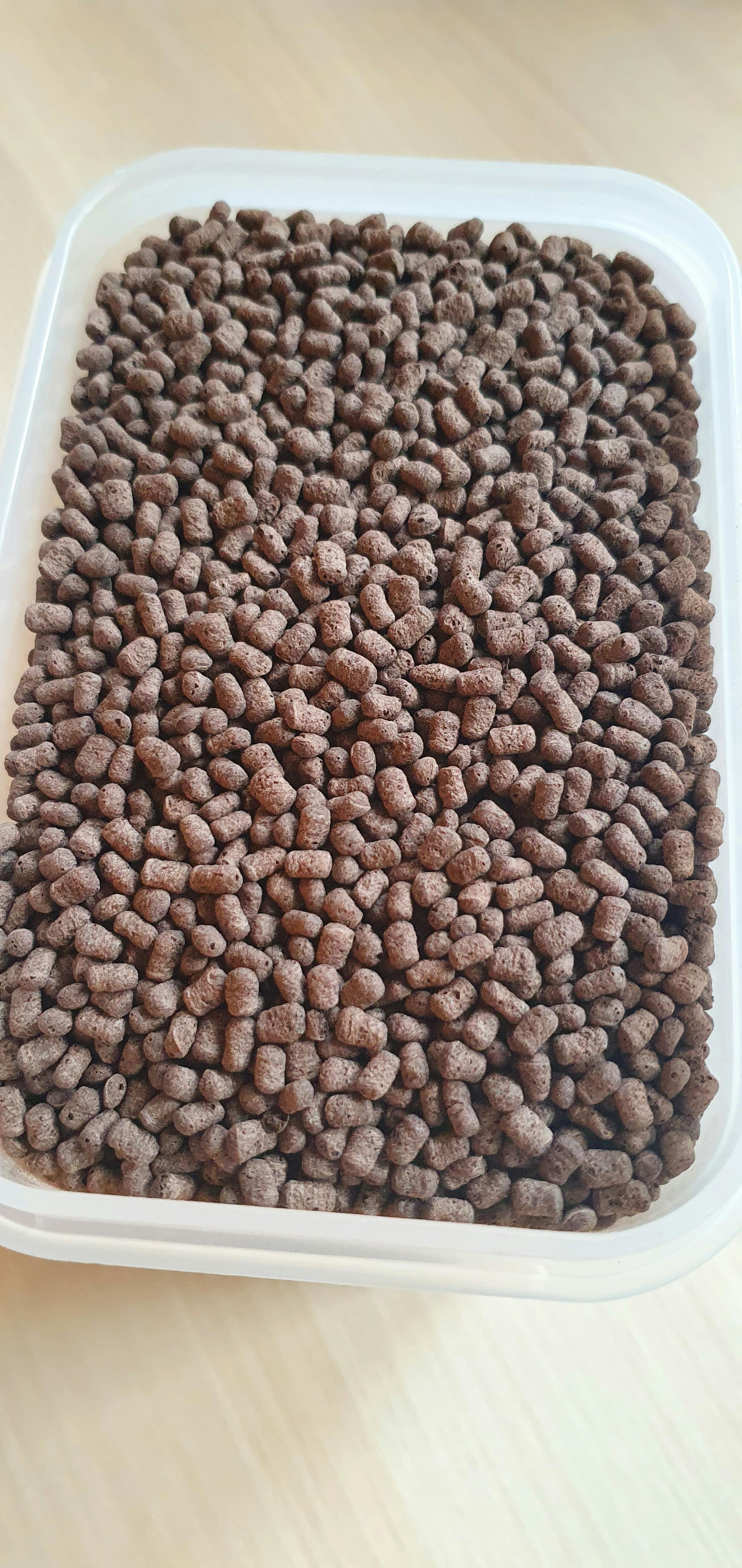 ein Plastikbehälter gefüllt mit braunen Kügelchen auf einem Tisch