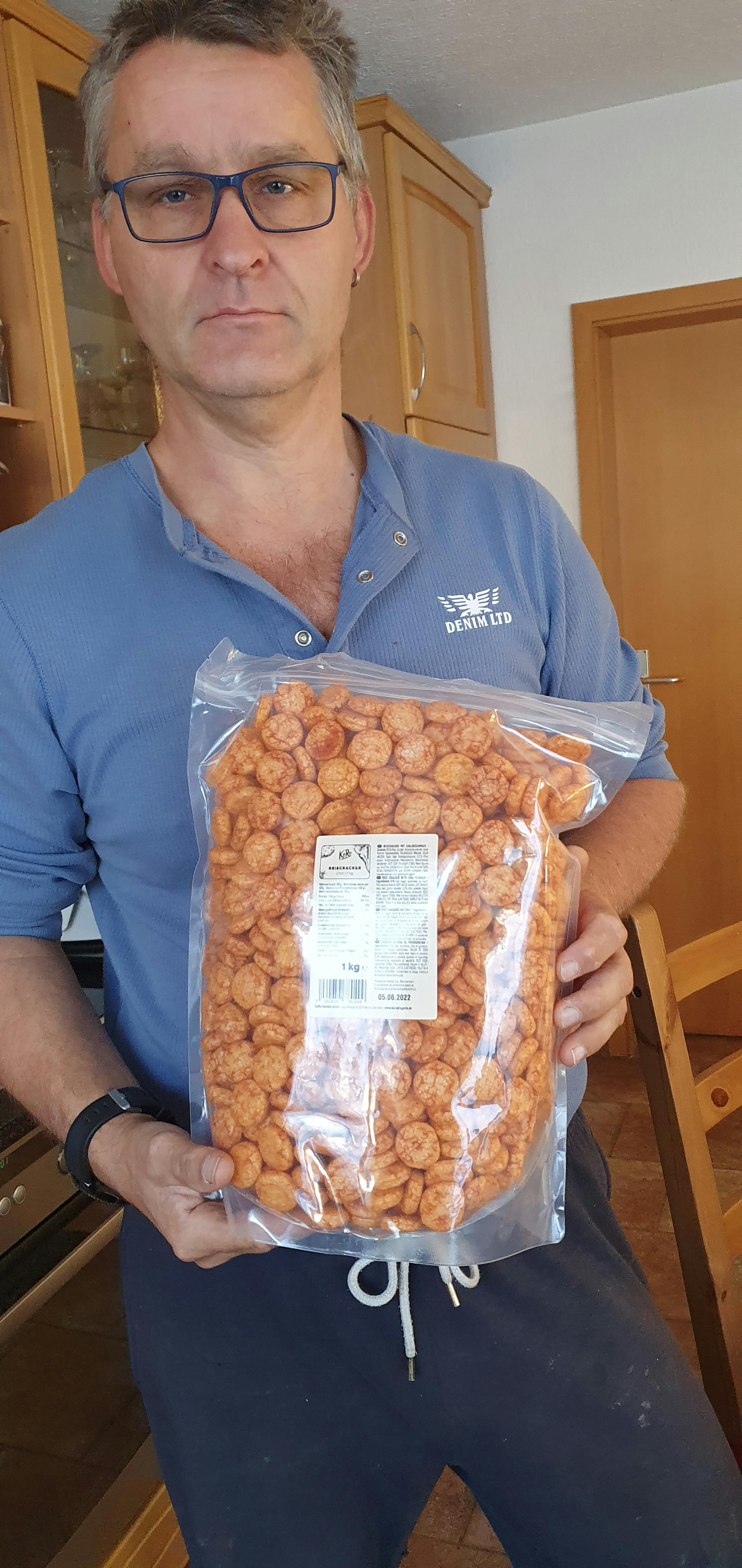 a man in a blue shirt holds a bag of snacks