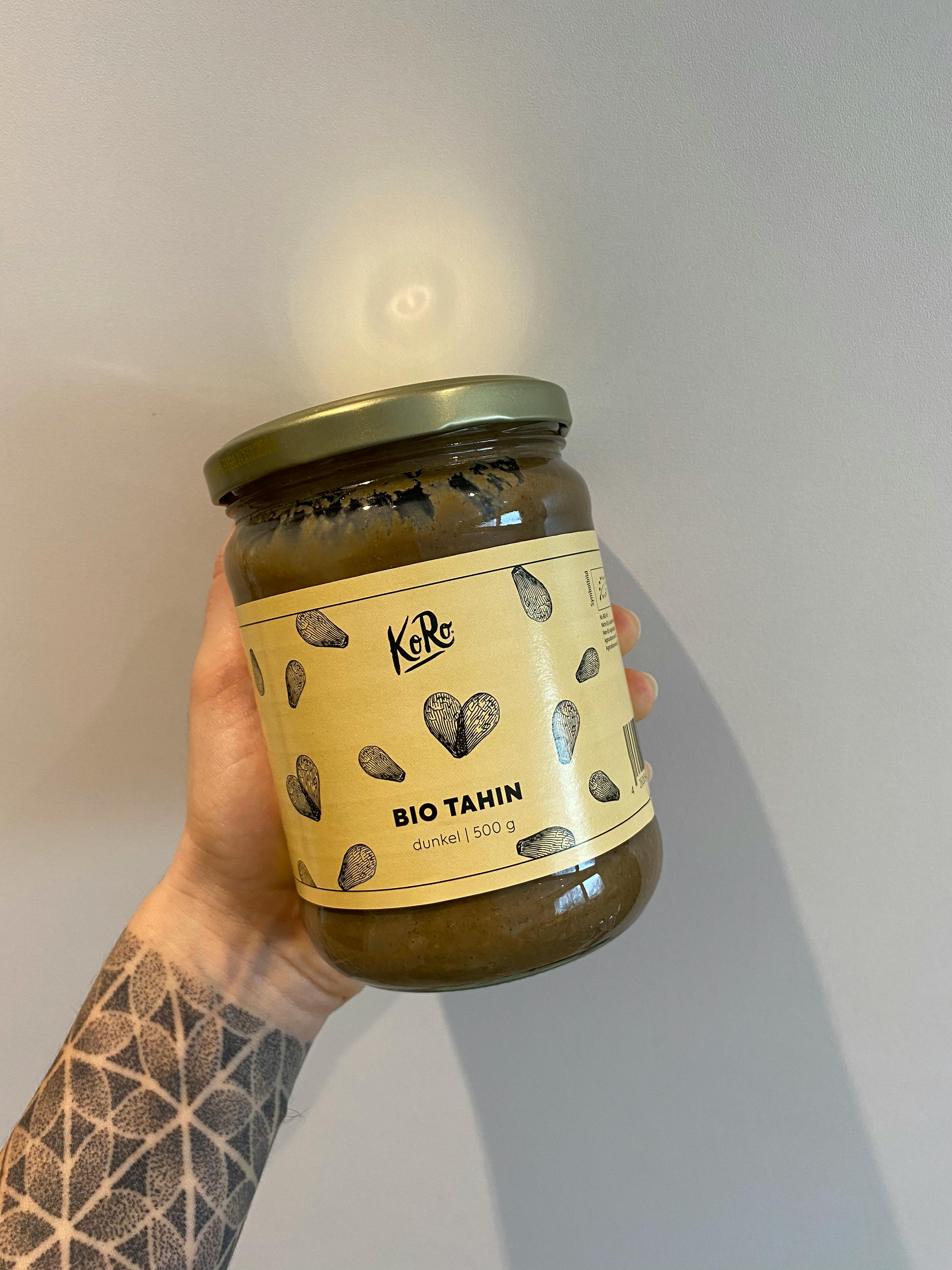 une personne tient un bocal de tahin bio dans sa main
