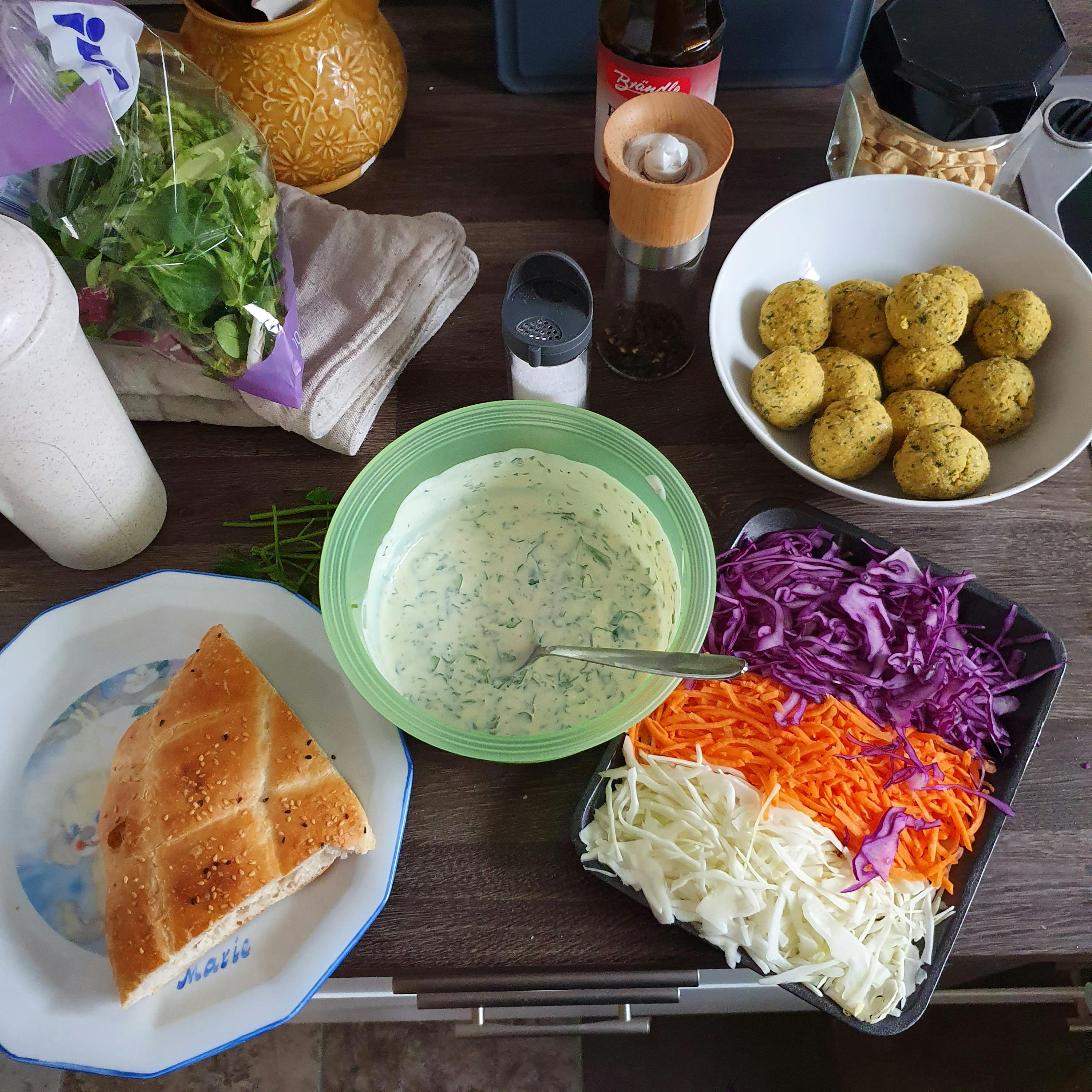 auf einem tisch steht eine flasche coca-cola neben einer schüssel mit falafeln
