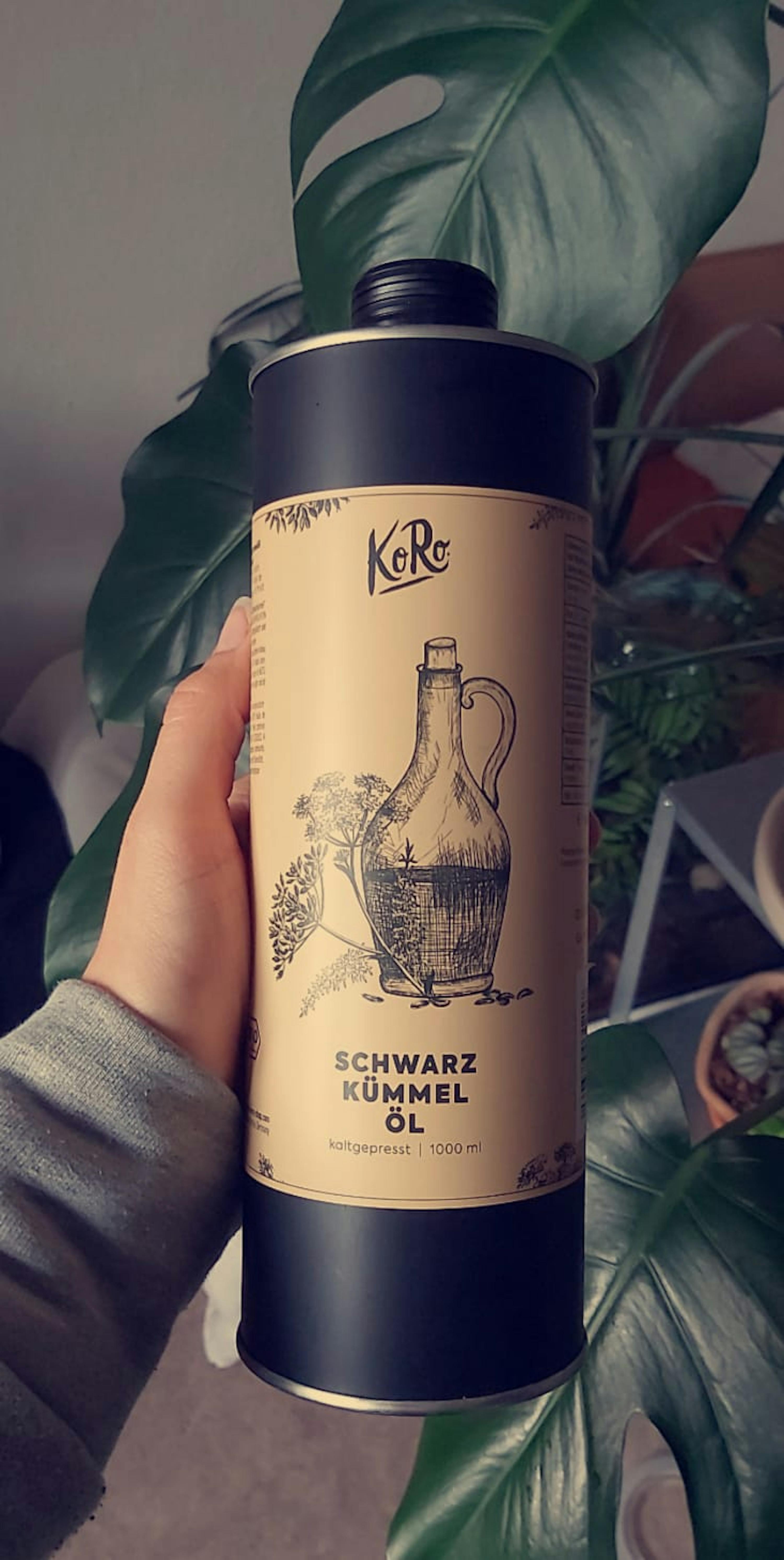 eine Person hält eine Dose schwarzkümmelöl in der Hand