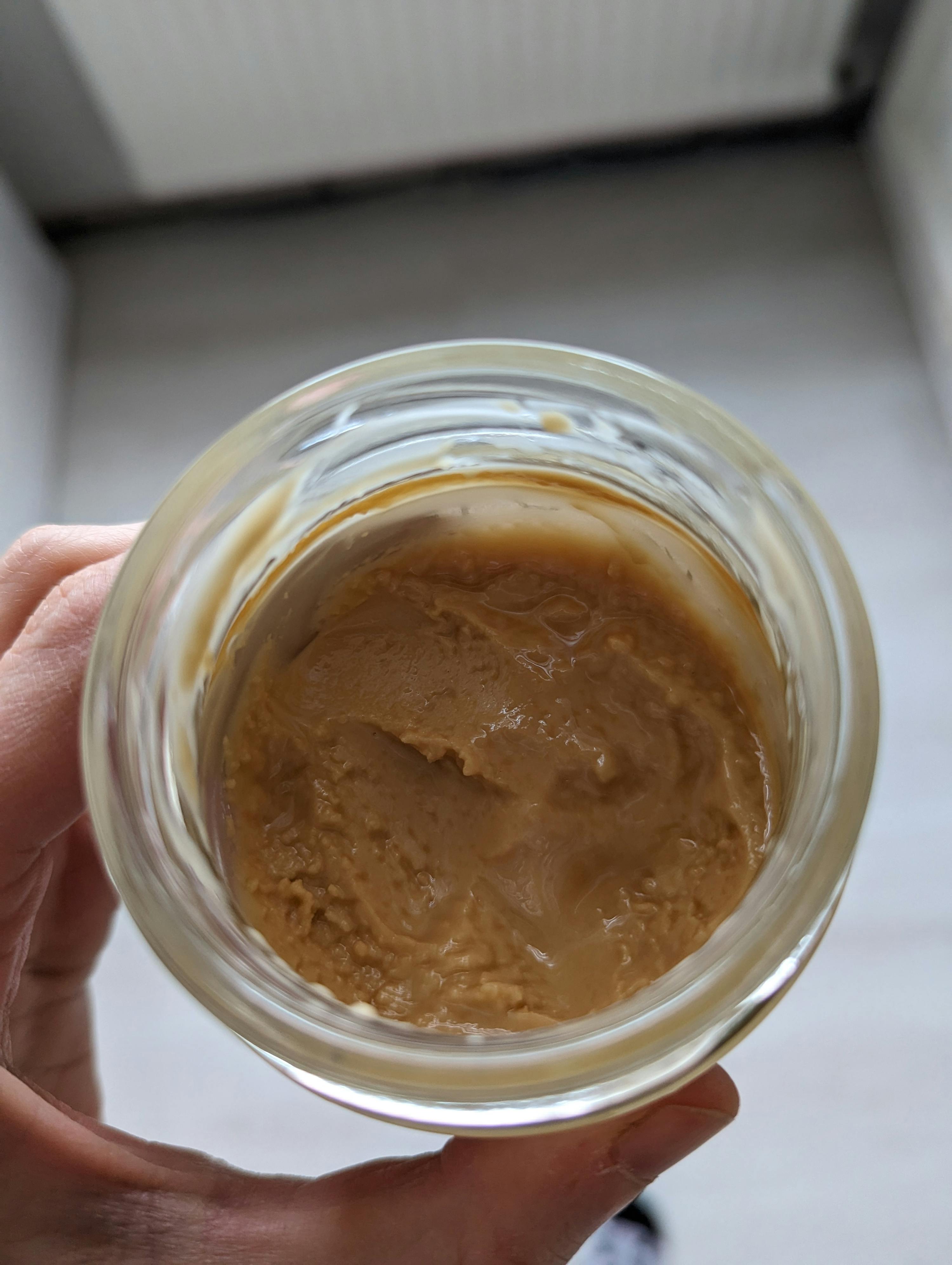 a person is holding a jar of peanut butter in their hand