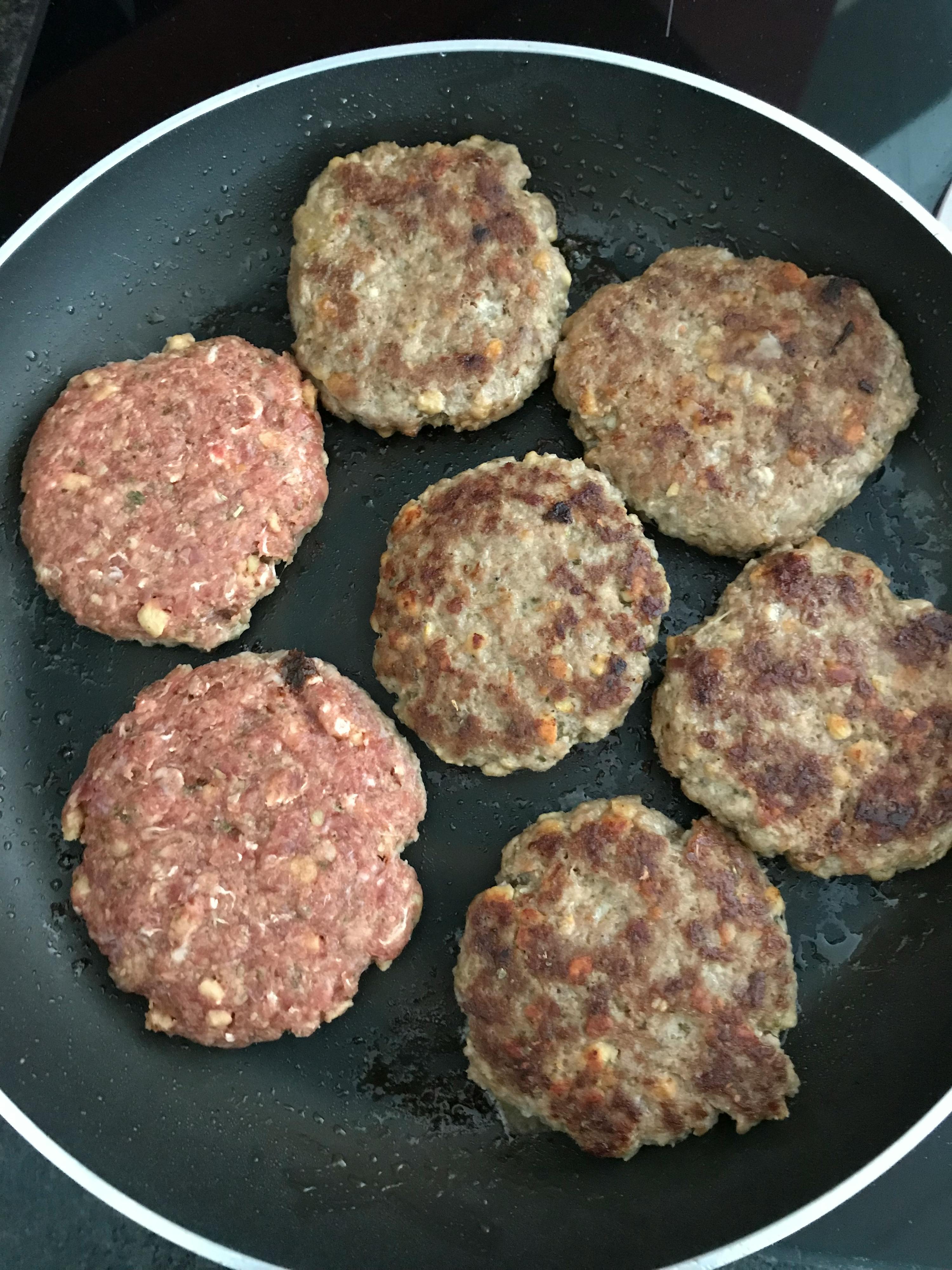 hamburger patties are cooking in a frying pan