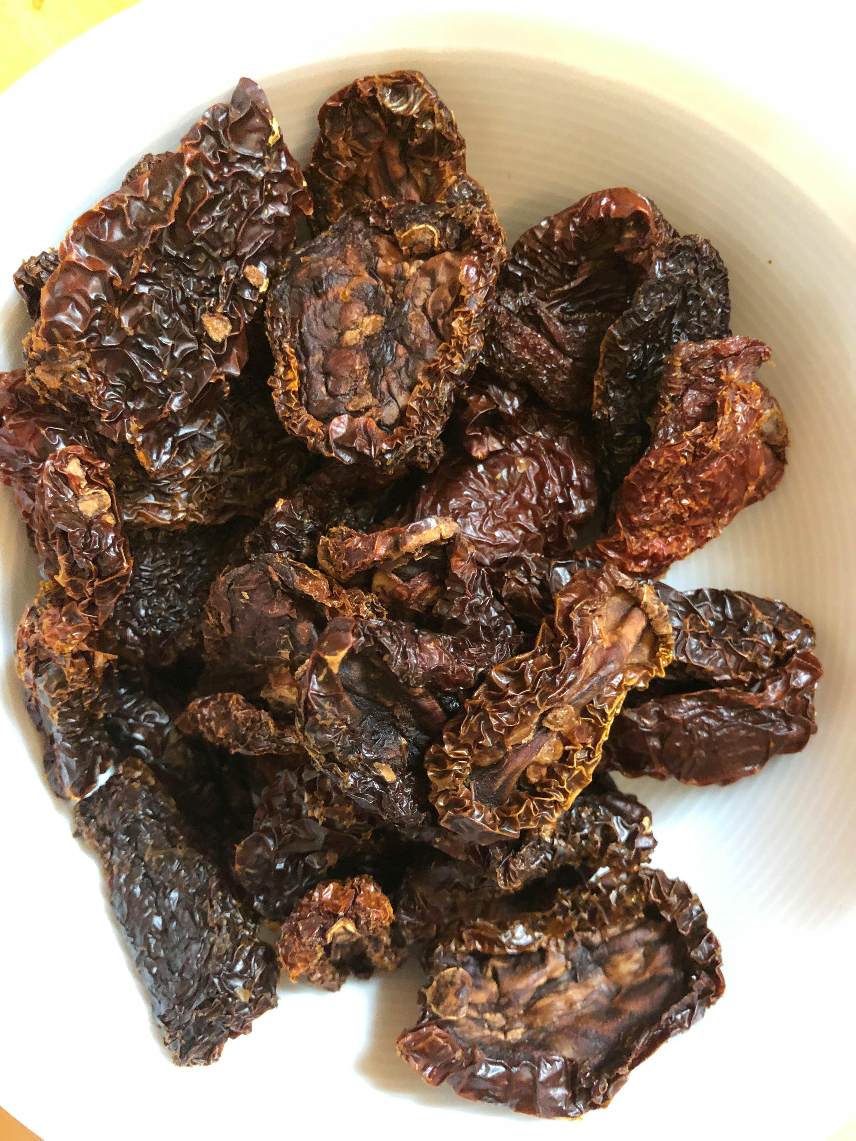 a white bowl filled with dried tomatoes with a yellow background