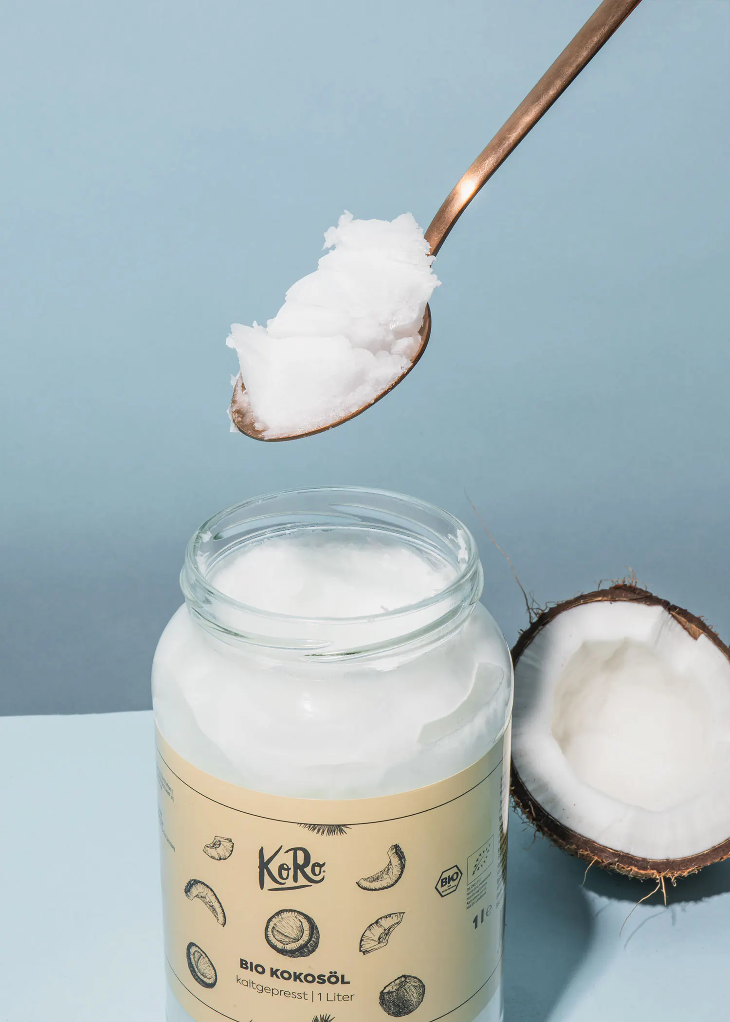 a spoonful of coconut oil is being poured into a jar of bio kokosöl
