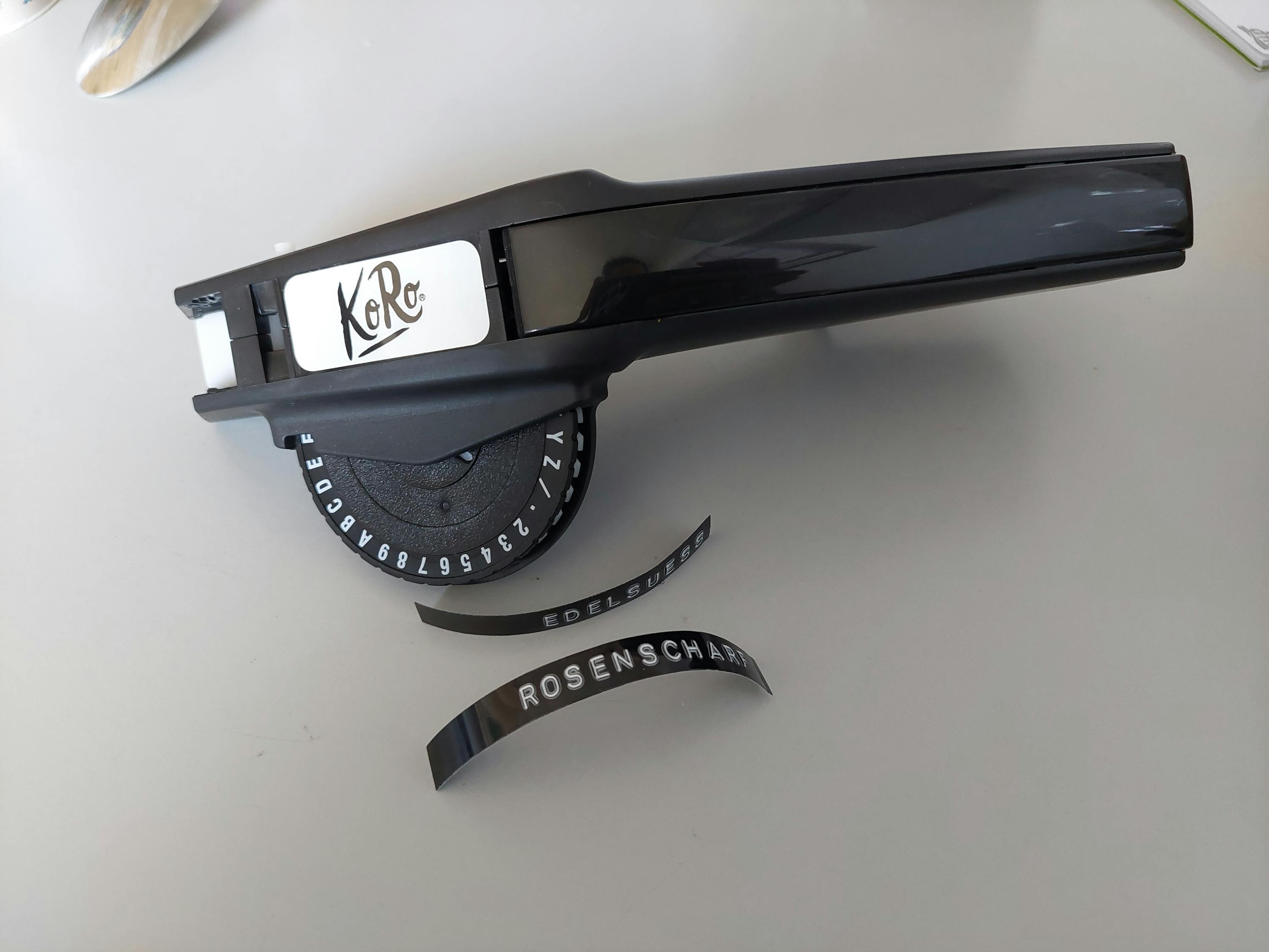 a black labeling machine with the word koro on it