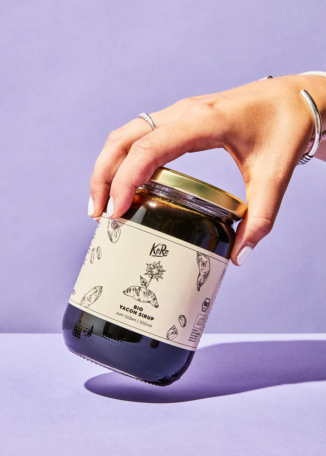 a person holding a jar of bio yacon syrup