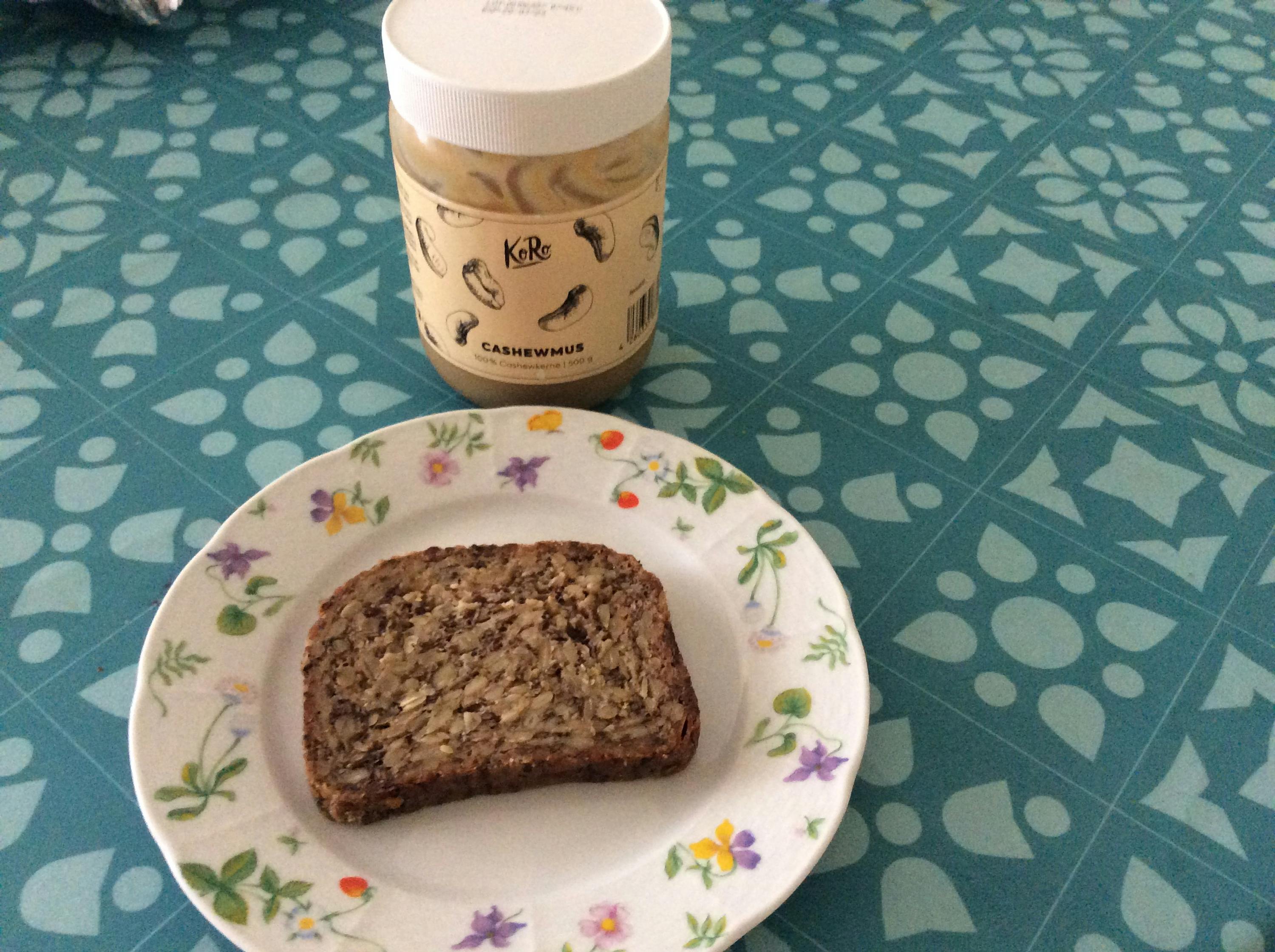 a plate with a slice of bread next to a jar of cashewmus