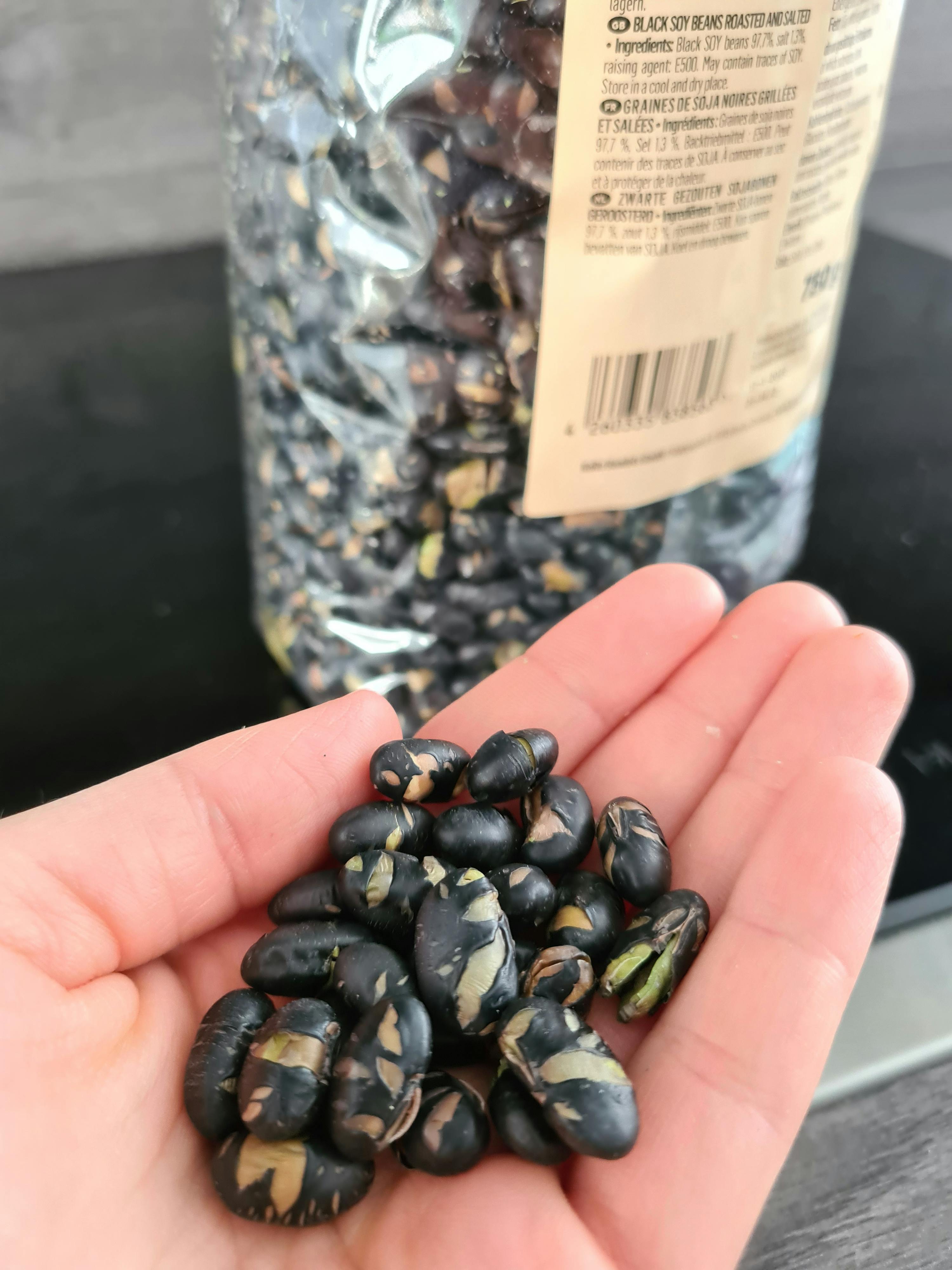 eine Person hält einen Haufen schwarzer Bohnen in der Hand