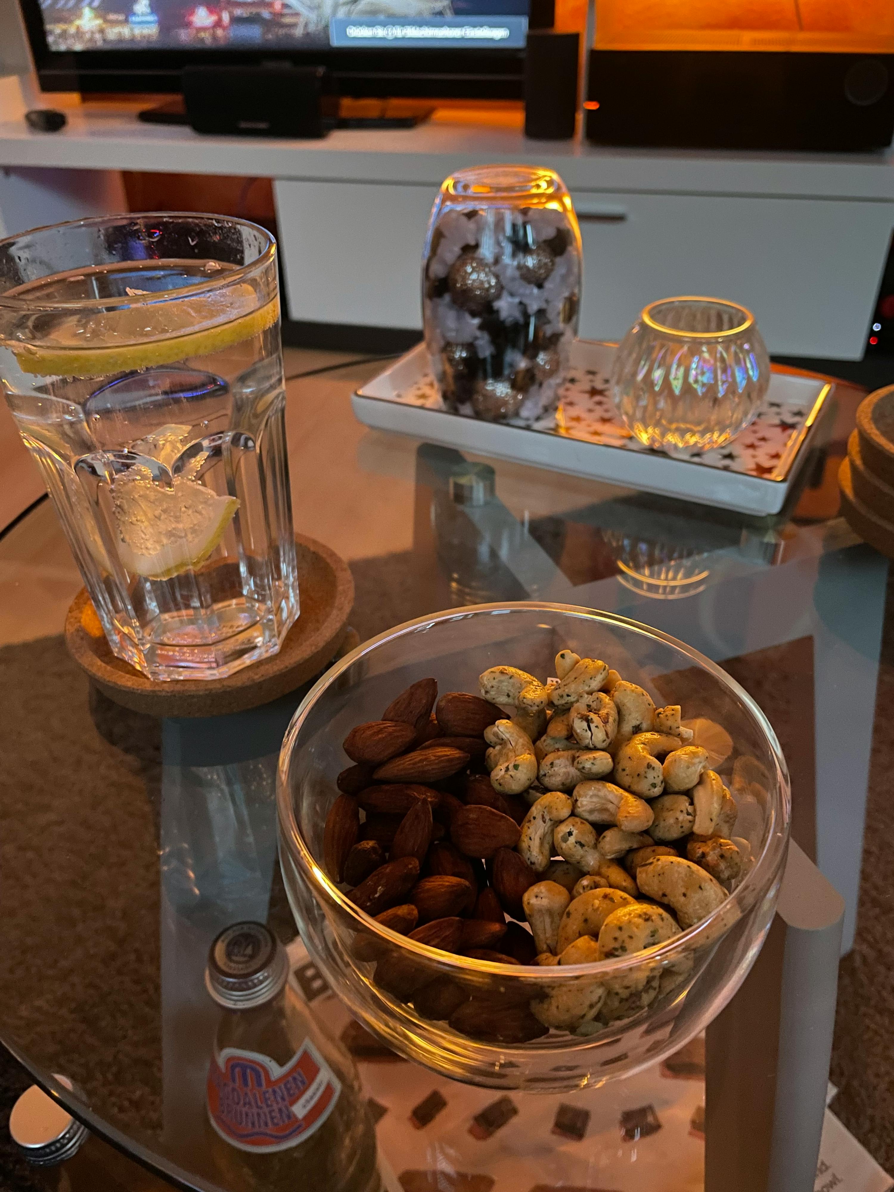 ein Couchtisch mit einer Schüssel Nüsse und einem Glas Wasser darauf