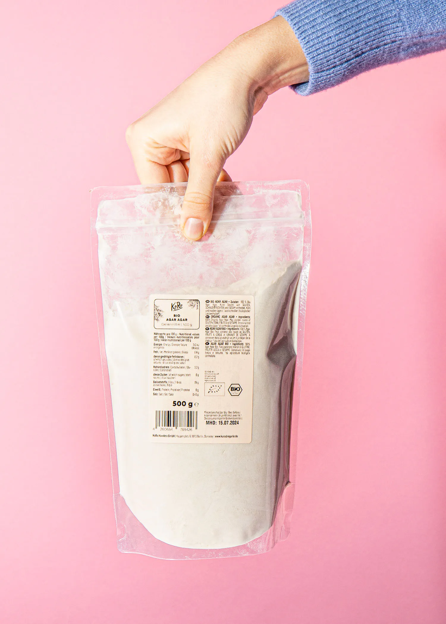 une personne tient un sac en plastique de 500 g de farine blanche