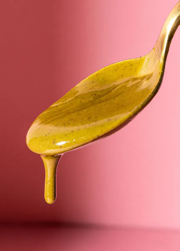 a spoon with a yellow liquid dripping from it