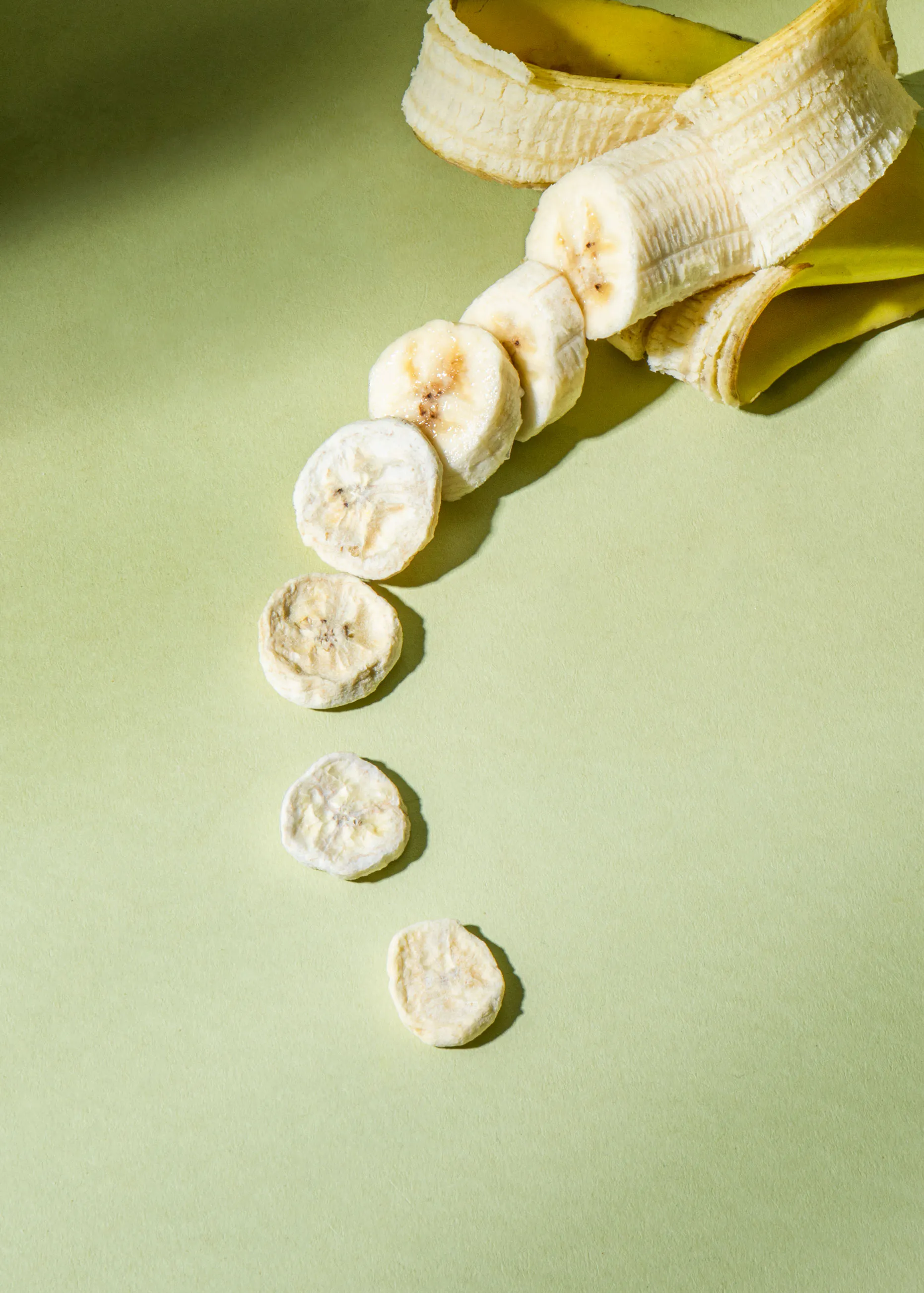 sliced bananas are lined up on a green surface